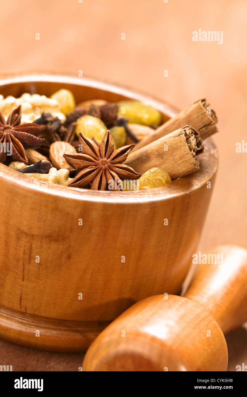 La cuisson des ingrédients tels que l'anis étoilé, de girofle, cannelle, amande, raisin, sultana et noyer en mortier à main en bois en face Banque D'Images
