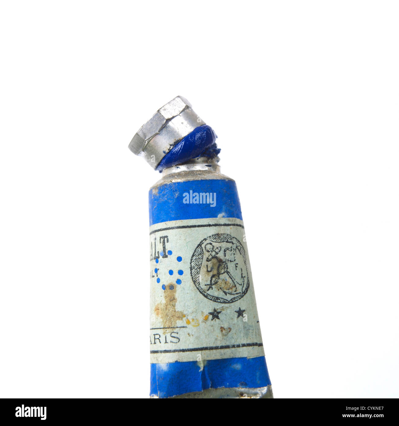 Vieux tube de peinture avec bouchon bleu et étiquette vintage reposant sur un fond blanc dans un cadre de studio lumineux Banque D'Images