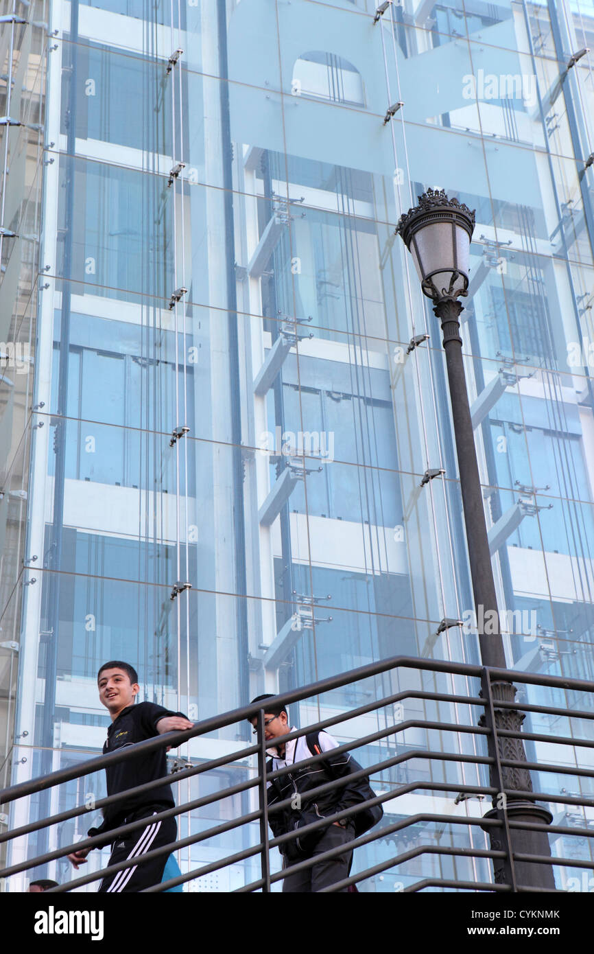 Deux jeunes garçons men smiling descendant un escalier extérieur avec garde-corps et façade en verre moderne comme arrière-plan, Madrid urbain moderne Banque D'Images