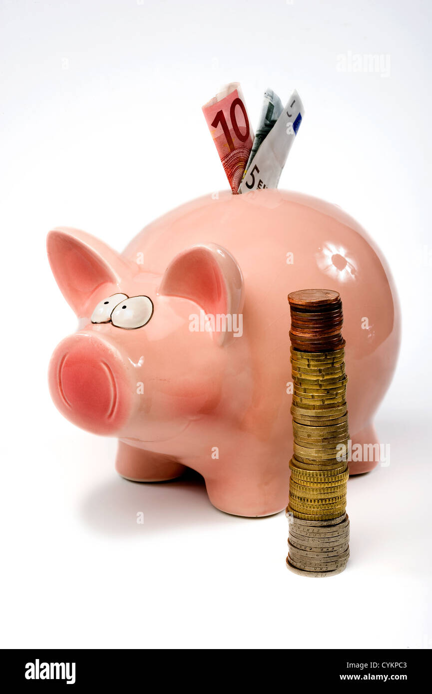 Un enregistrement de porc est debout derrière agrafé pièces en euro Banque D'Images