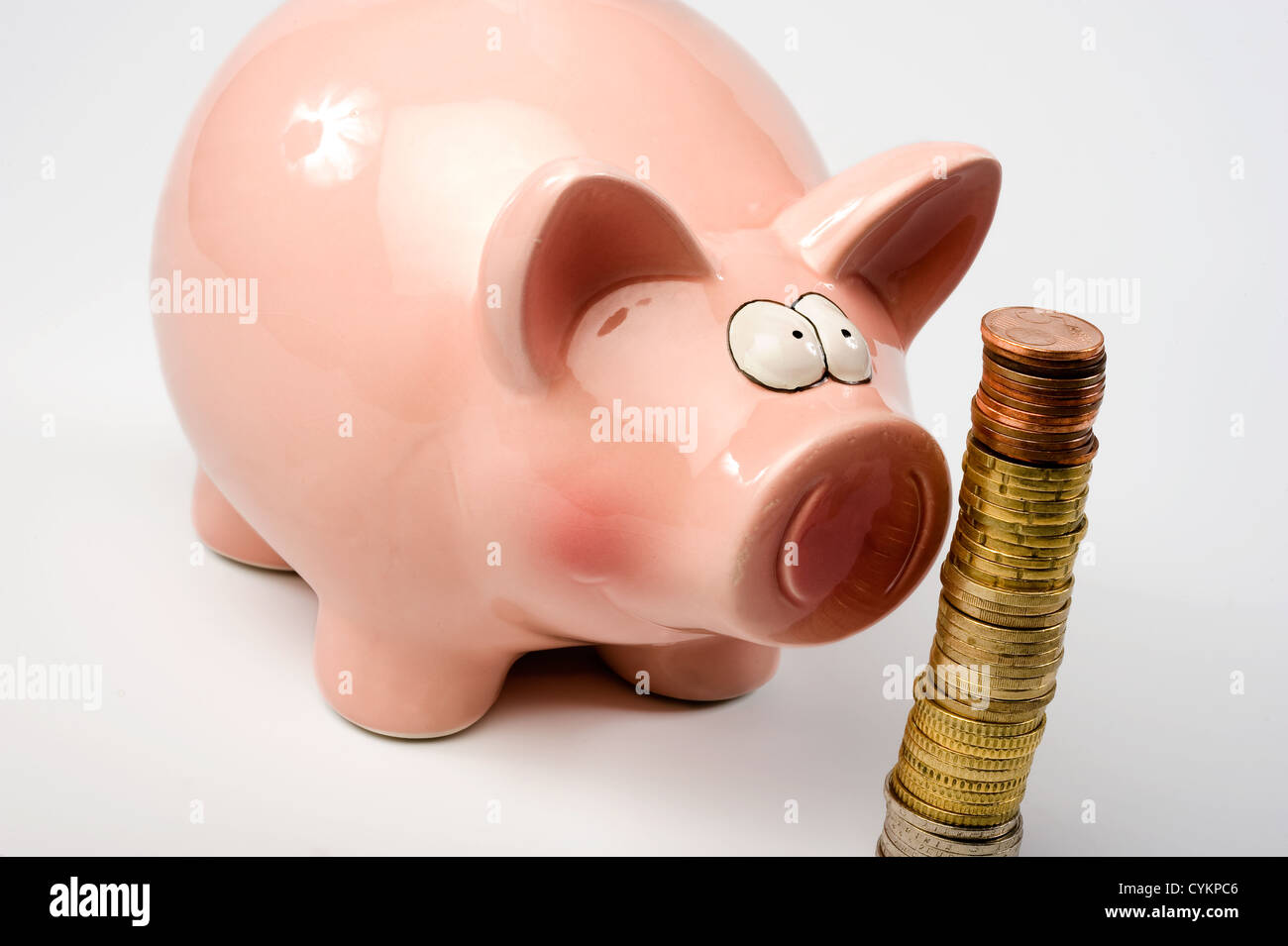 Un enregistrement de porc est agrafé à regarder les pièces en euros Banque D'Images