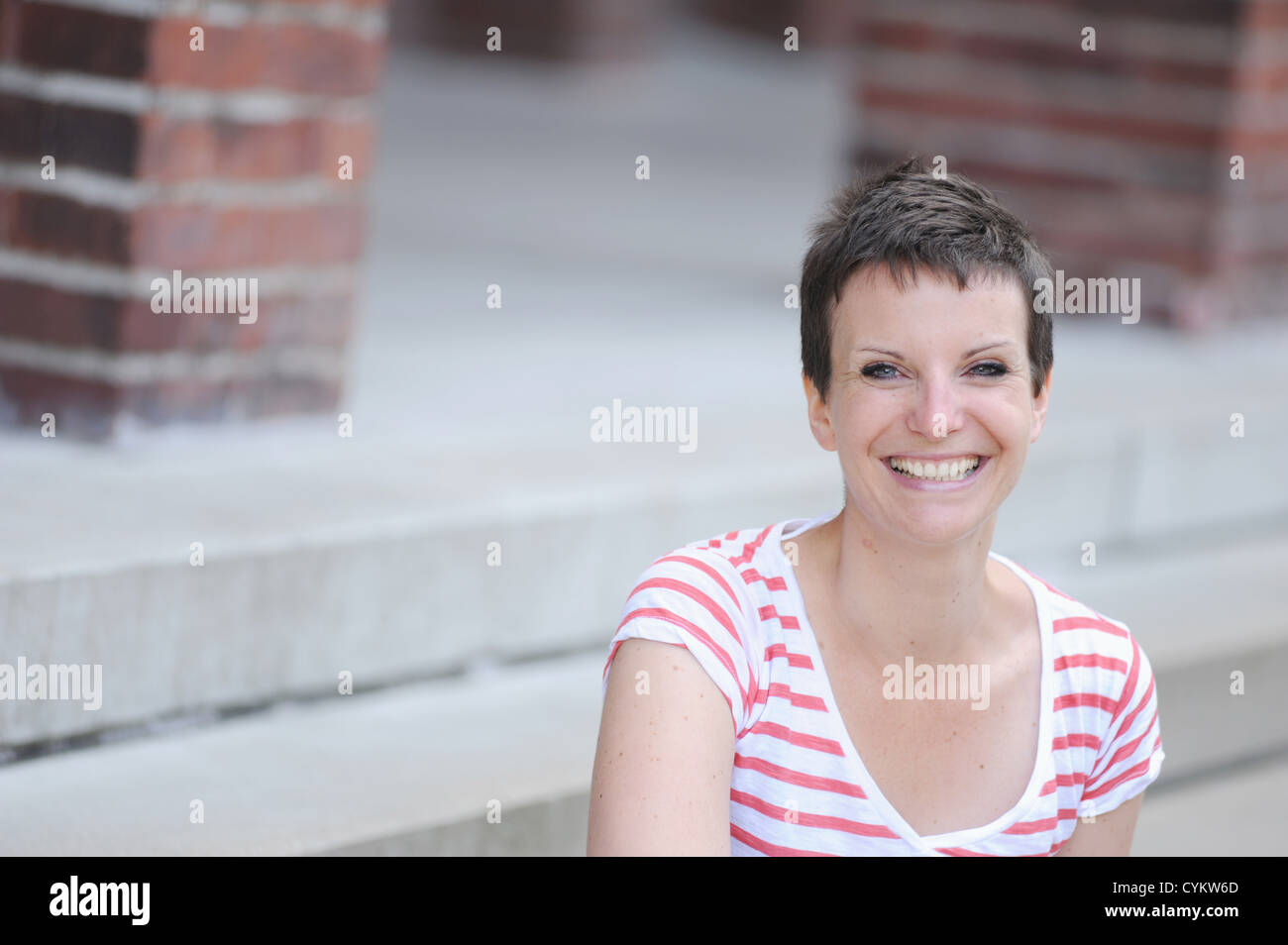 Smiling woman sitting on city street Banque D'Images