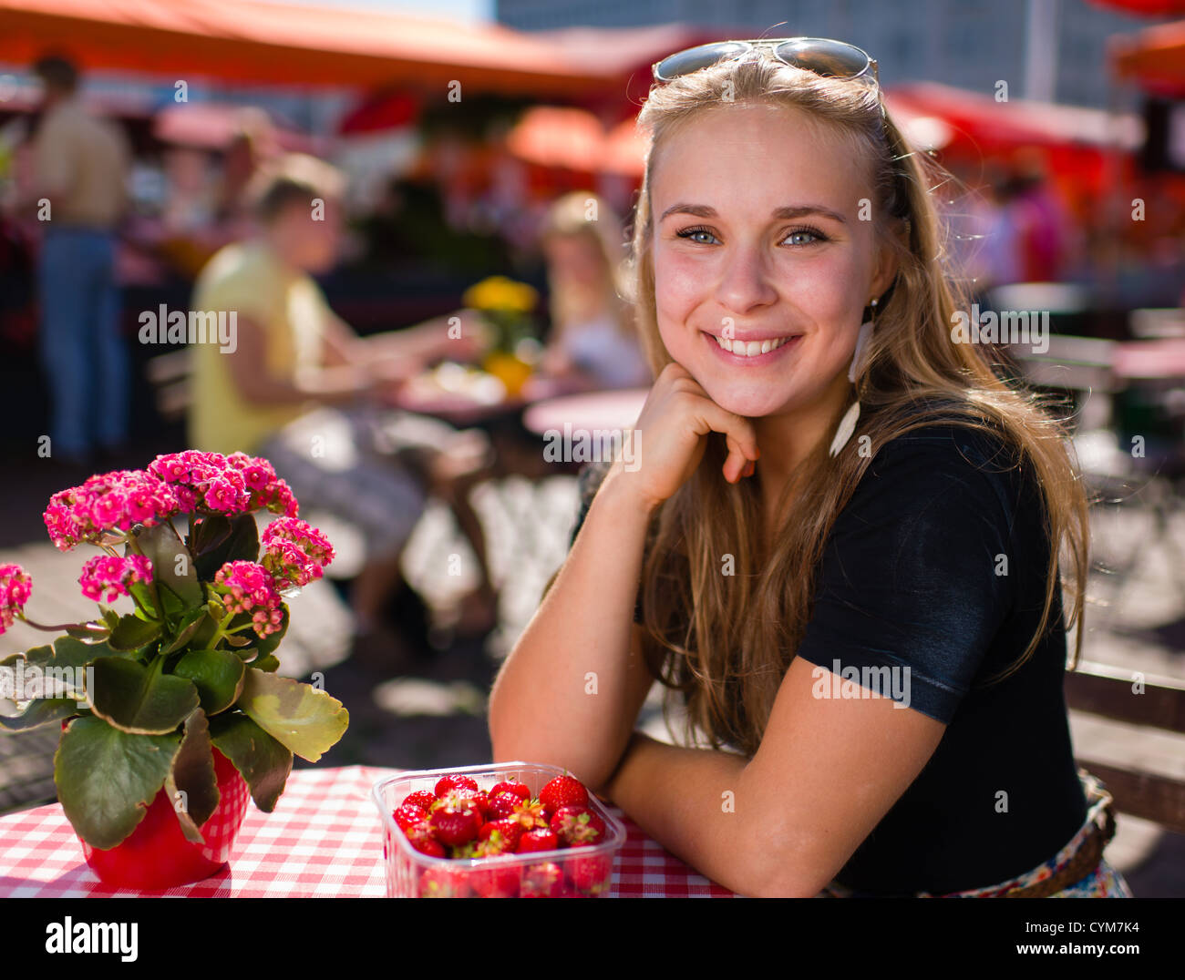 Belle jeune fille s'assied sur le marché d'un café et elle ont fraises savoureuses Banque D'Images