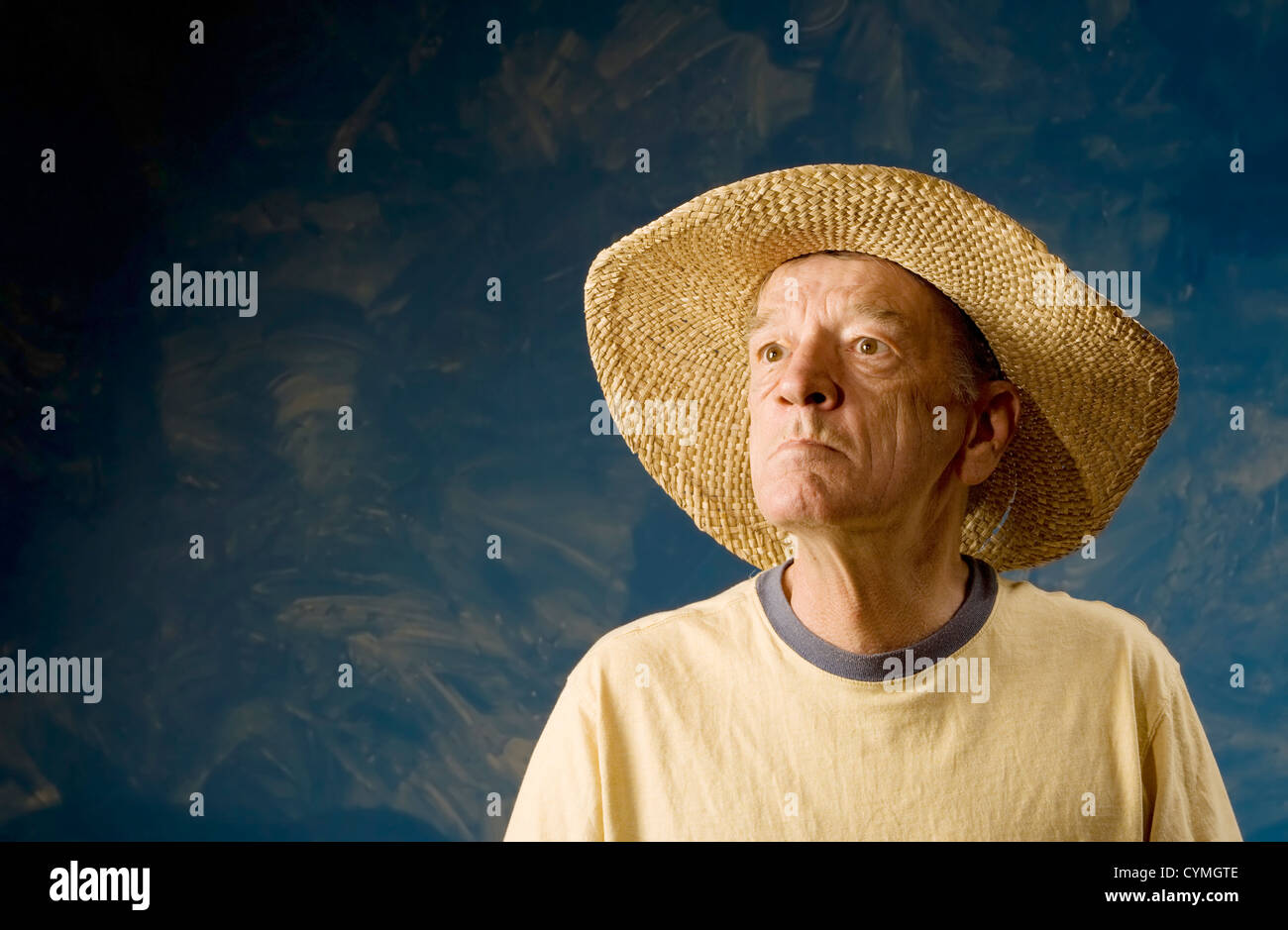 Man dans un chapeau de paille à l'avant du mur ensemble bleu Banque D'Images