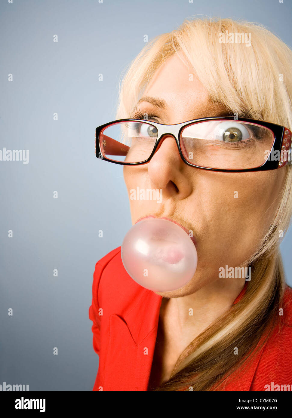 Femme en rouge avec des verres soufflé une bulle Banque D'Images