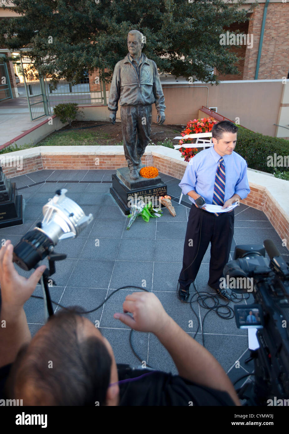 Journaliste de télévision n'en rapport d'une statue d'avant le légendaire entraîneur de football de l'Université du Texas Darrell royal après la mort de Royal Banque D'Images