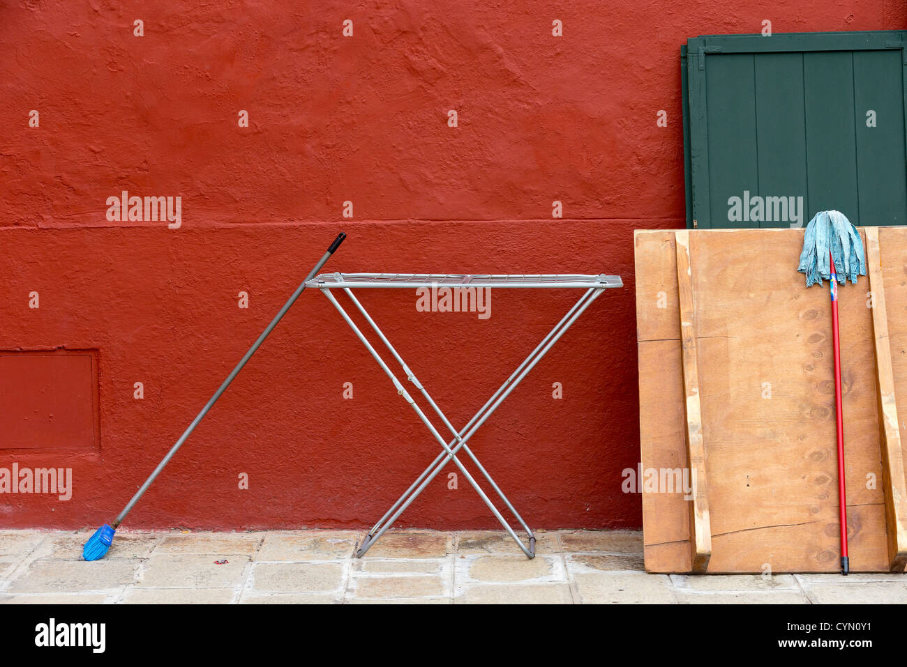 Du matériel de repassage et de séchage vadrouilles dans la rue à l'extérieur d'une maison nouvellement peint de couleur rouille, de Burano, Venise Banque D'Images
