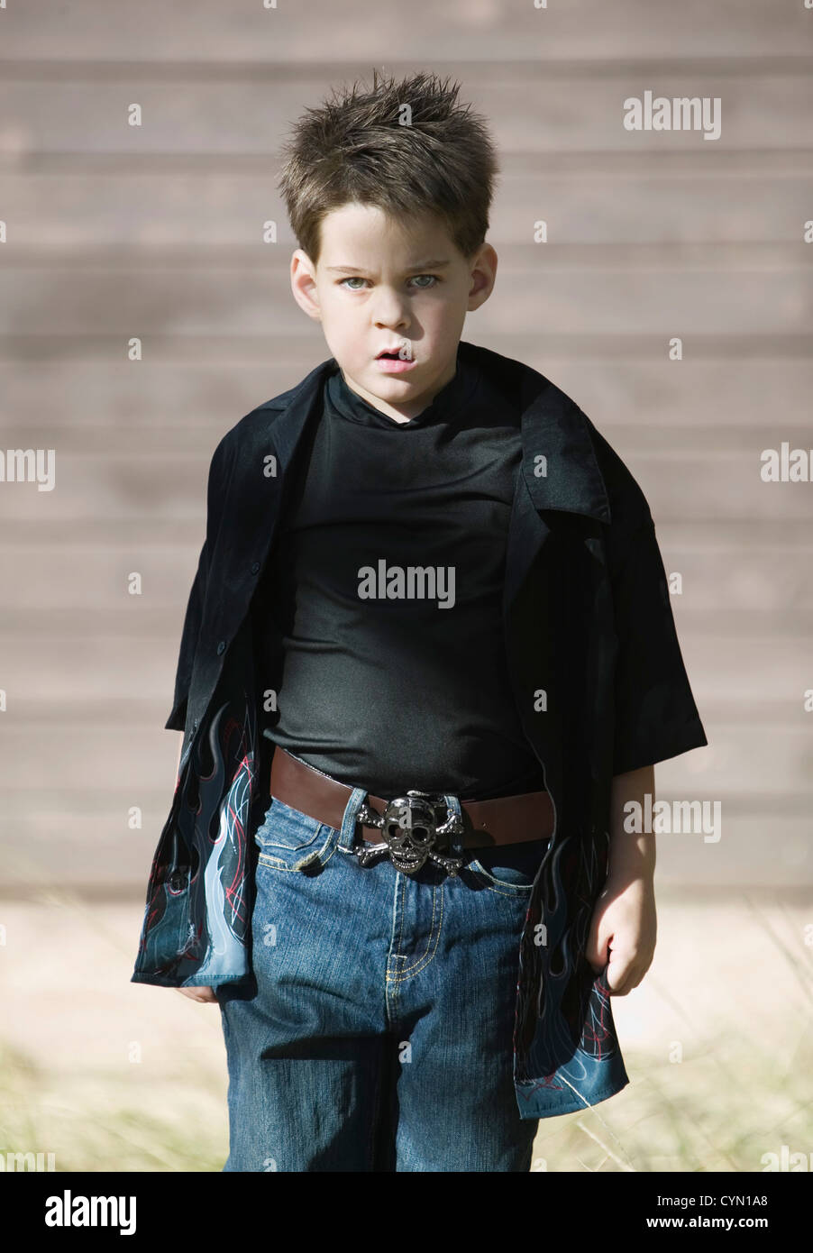Jeune garçon avec une attitude de défi de porter une chemise noire et une  boucle de ceinture de pirate Photo Stock - Alamy