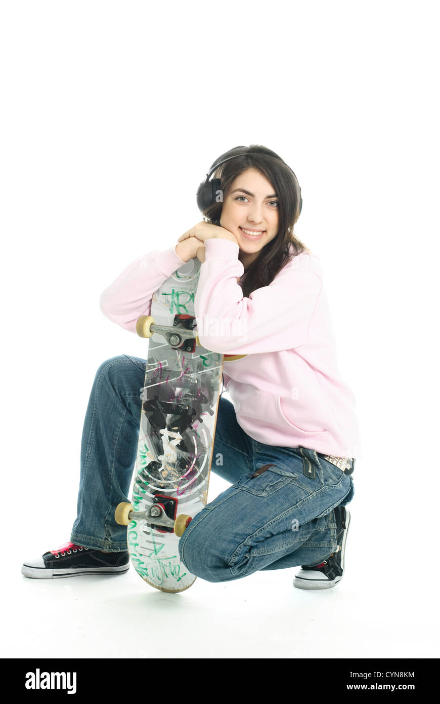 Teenage girl wearing earphones et tenant un skate board Banque D'Images