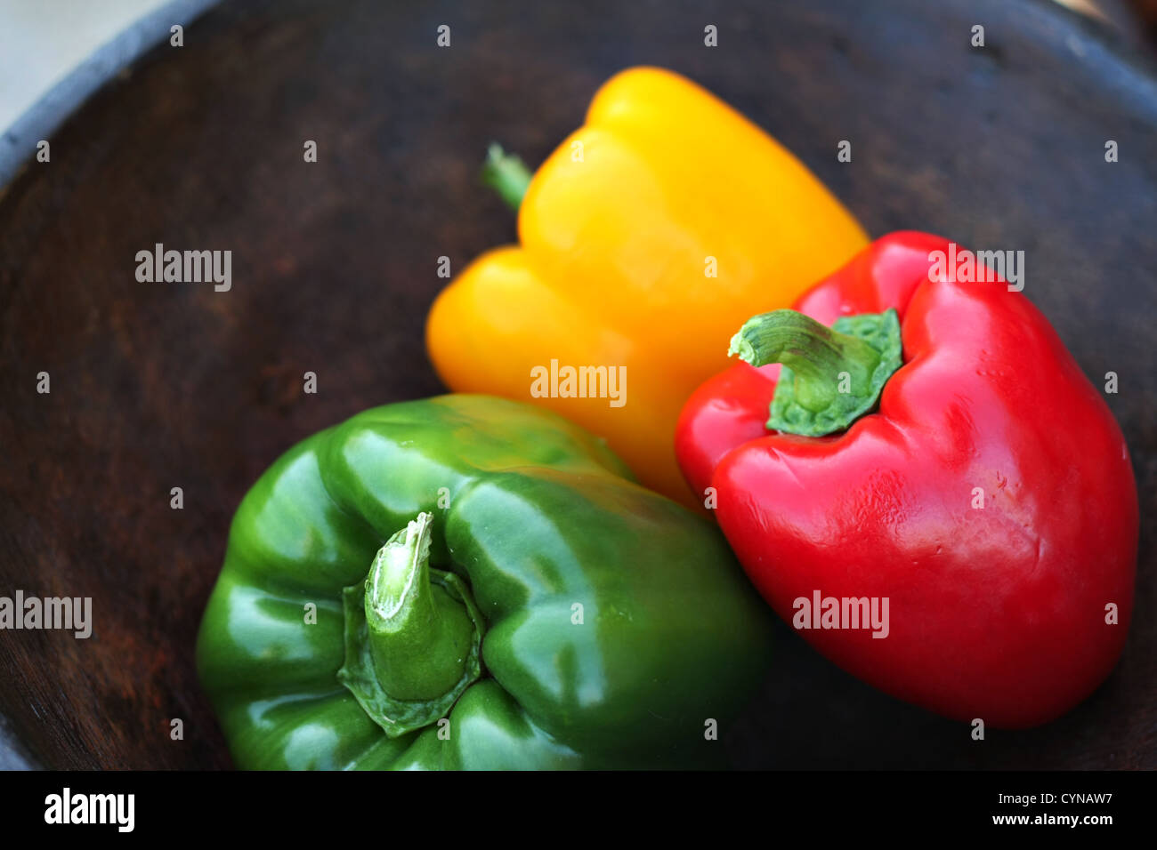 Poivrons colorés dans un bol en bois sculpté à la main Banque D'Images