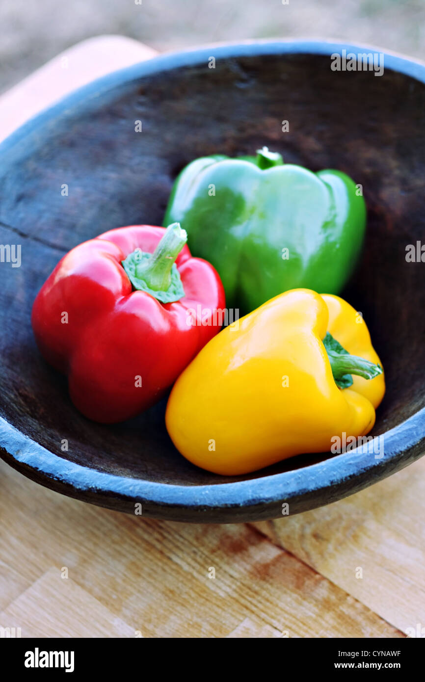 Poivrons colorés dans un bol en bois sculpté à la main Banque D'Images