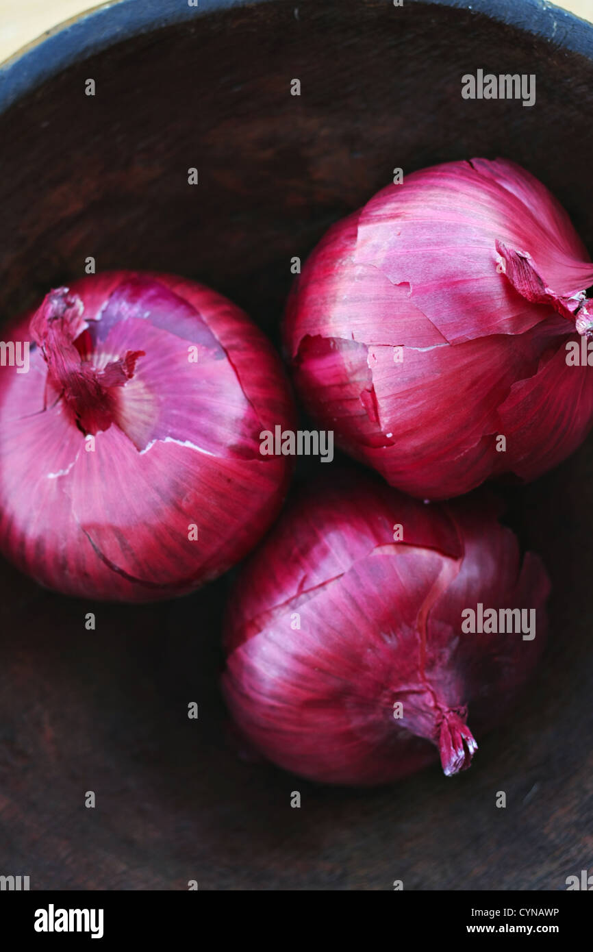 Oignons rouges dans un bol en bois sculpté à la main Banque D'Images