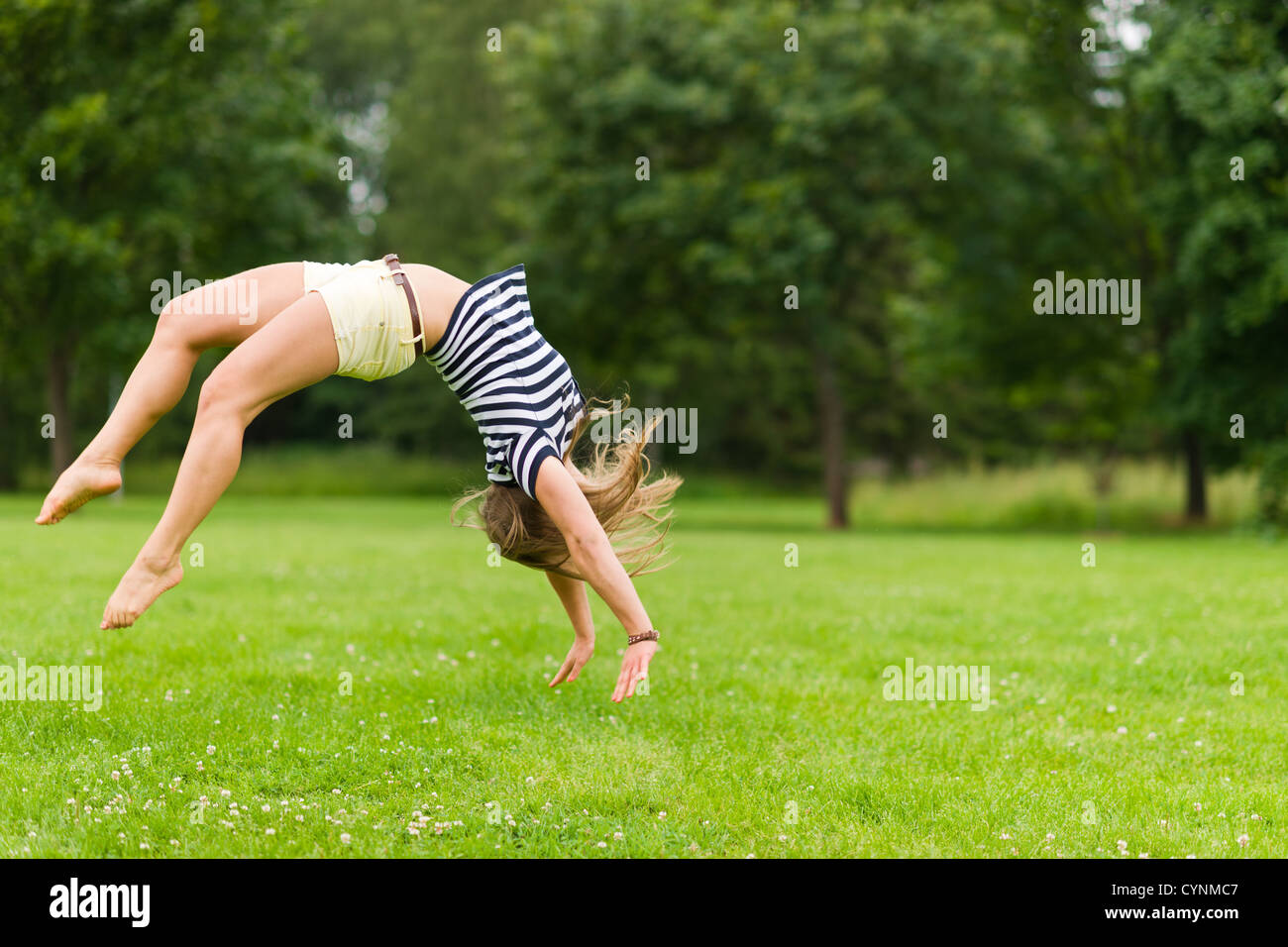 Jeune fille sportive saut en arrière dans le parc, avec l'image de la profondeur de champ étroite Banque D'Images