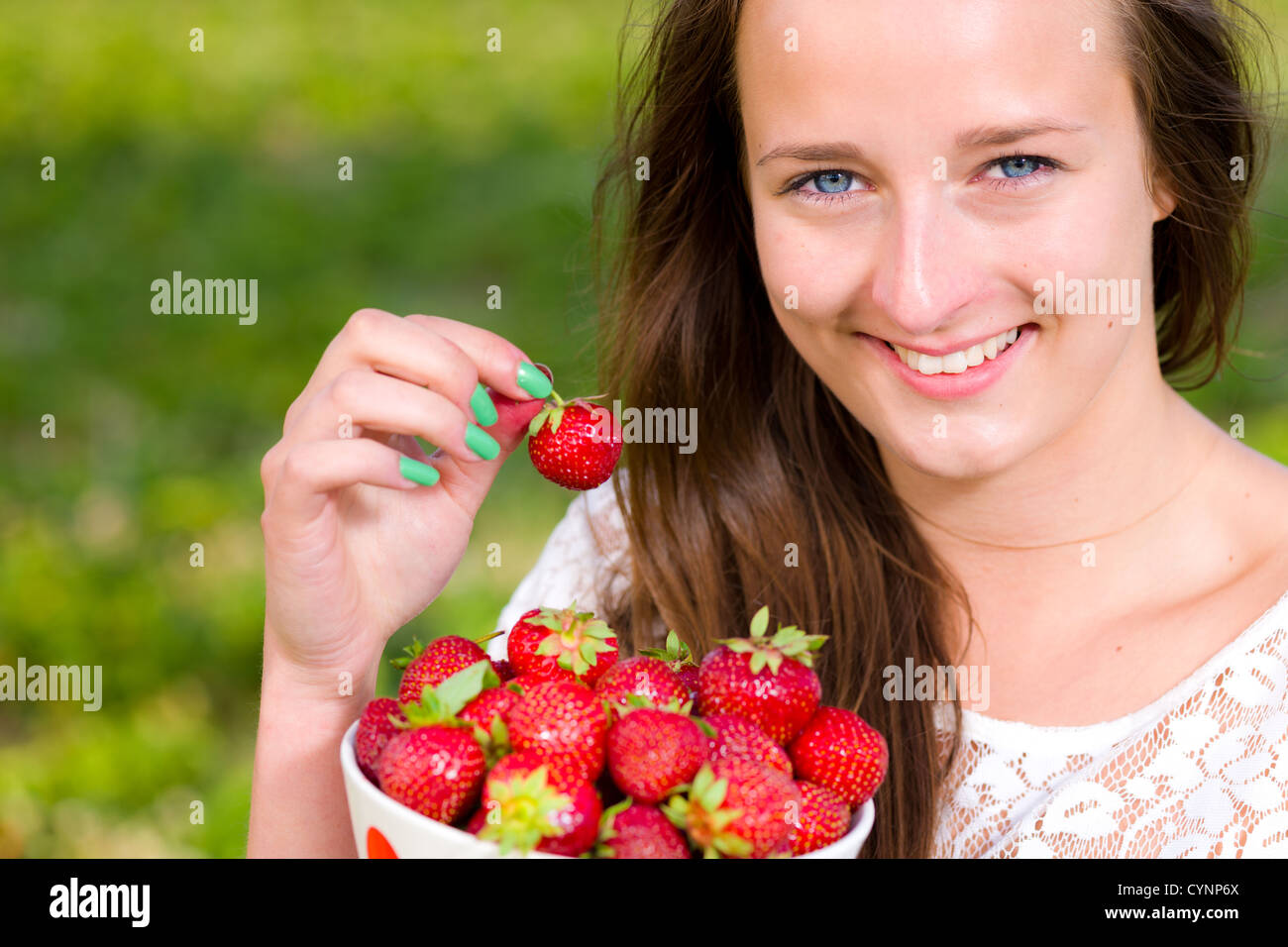 Belle fille ramasser une fraise à partir d'un bol, mettre l'accent sur les yeux Banque D'Images