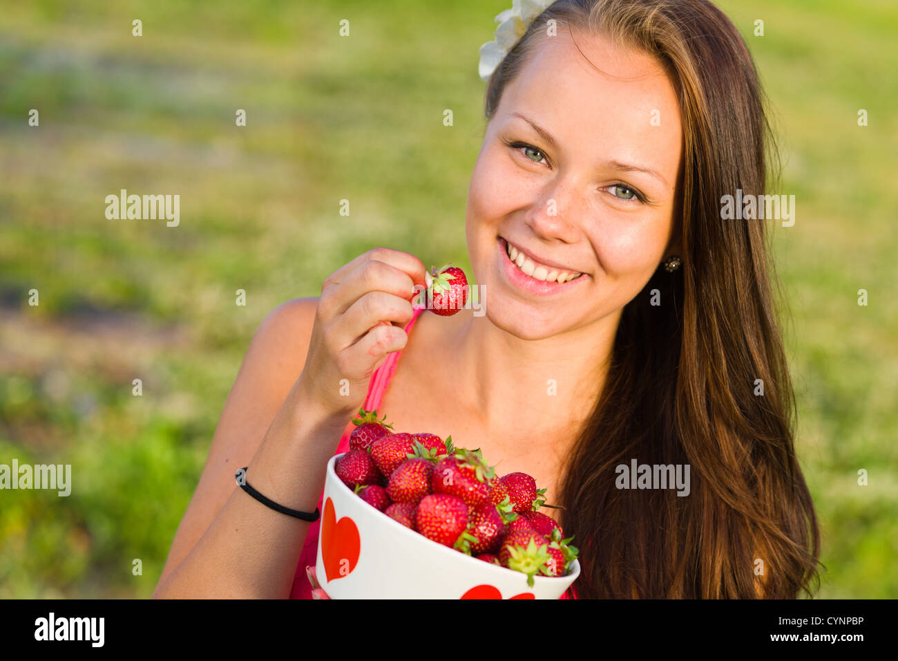 Belle fille ramasser une fraise à partir d'un bol, mettre l'accent sur les yeux, l'image paysage Banque D'Images