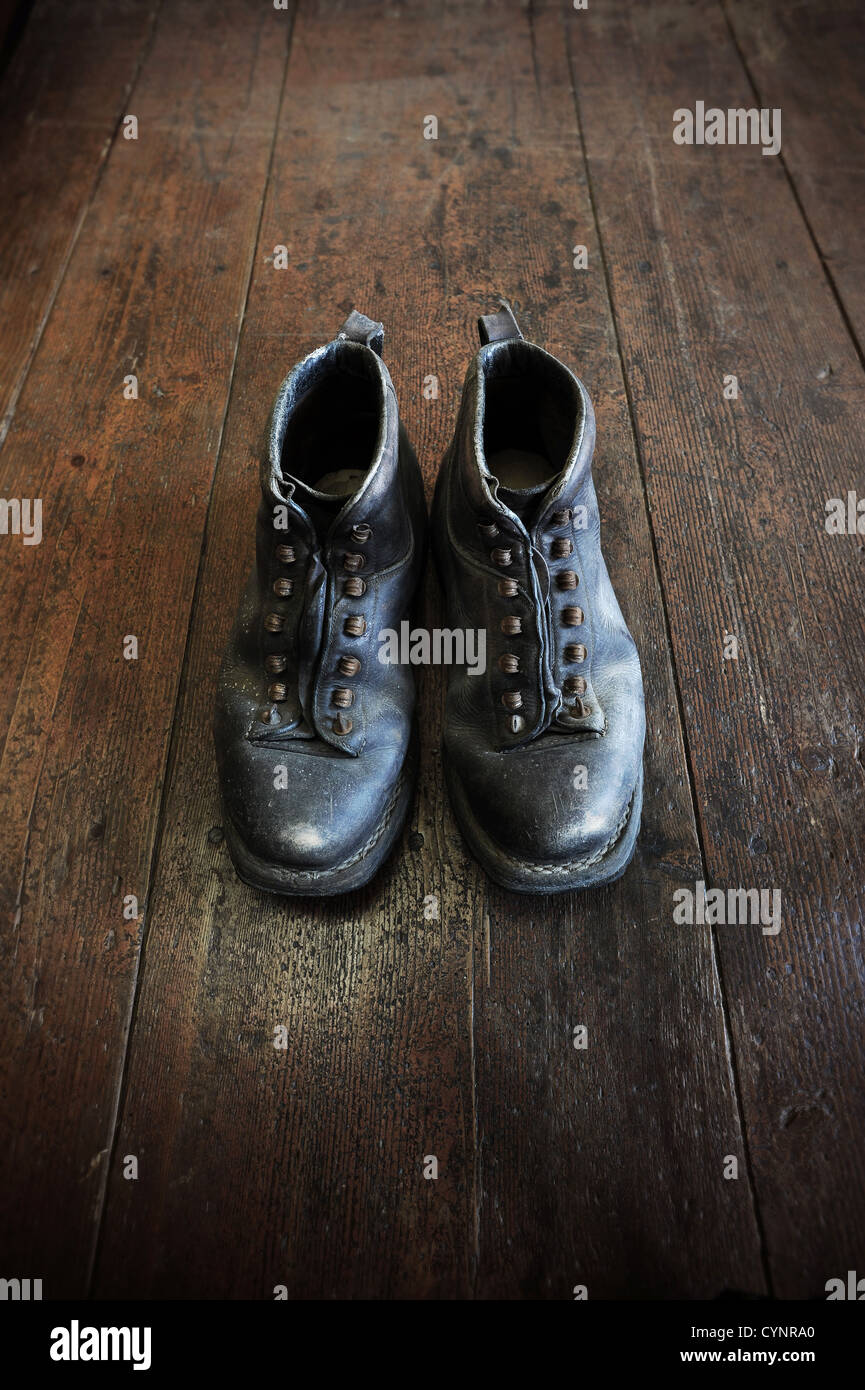 Une vieille paire de bottes en cuir sur un vieux plancher en bois Banque D'Images