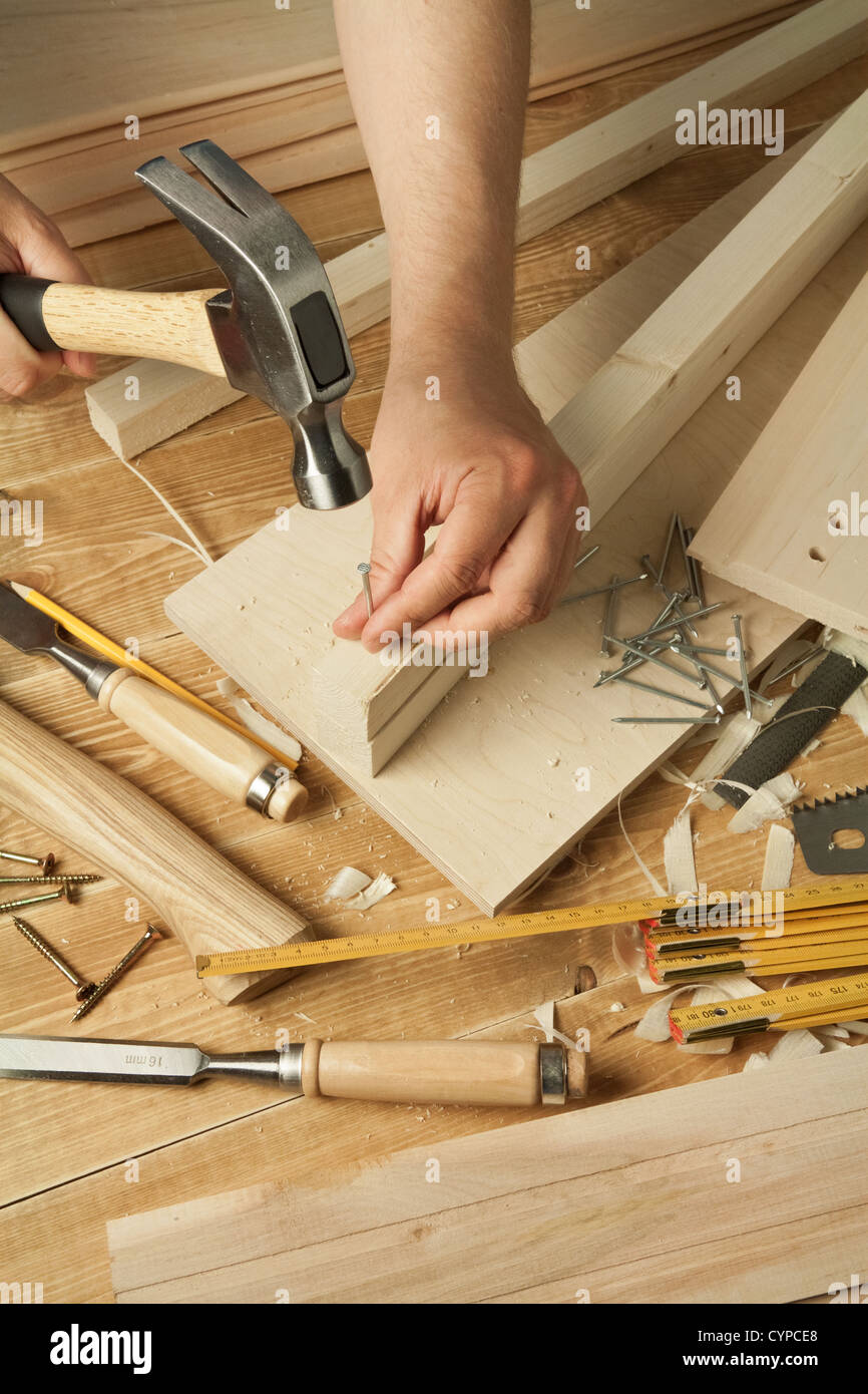 Atelier en bois avec la table d'outils. Man's arms marteler un clou Banque D'Images