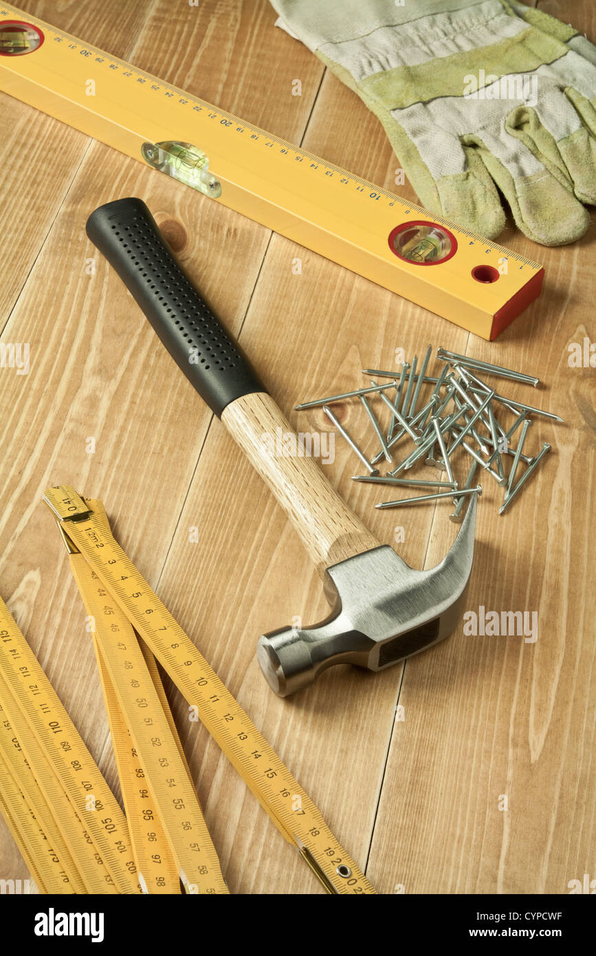 Hammer, règle, niveau, des gants et des ongles sur plancher en bois Banque D'Images