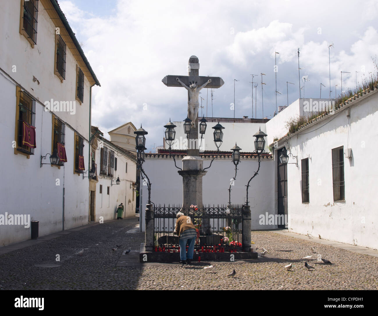 Calvaire en pierre avec adorateur arranging flowers, Plaza de Los Capuchinos, Cordoba Andalousie Espagne Banque D'Images