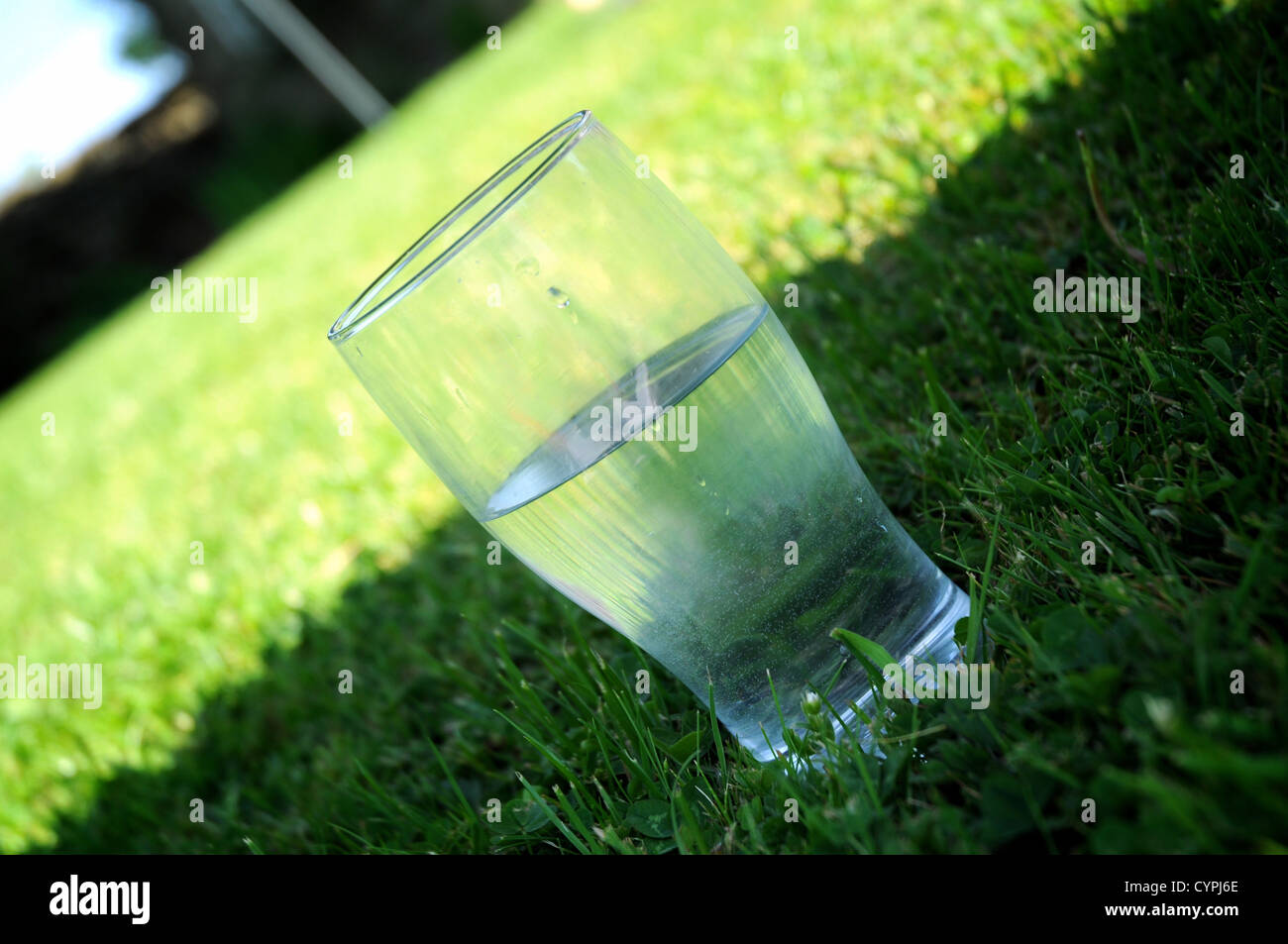 Pinte verre d'eau, assis à l'ombre sur l'herbe sur une chaude journée d'été Banque D'Images