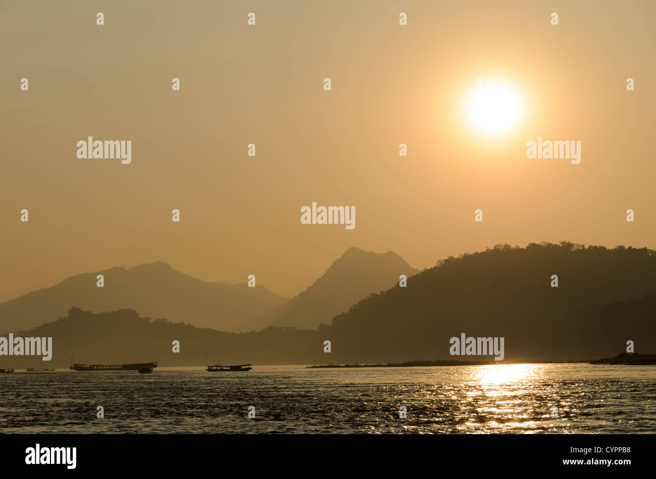 LUANG PRABANG, Laos - Coucher de soleil sur le Mékong près de Luang Prabang, au centre du Laos, avec moutnains et bateaux qui se profile. Banque D'Images
