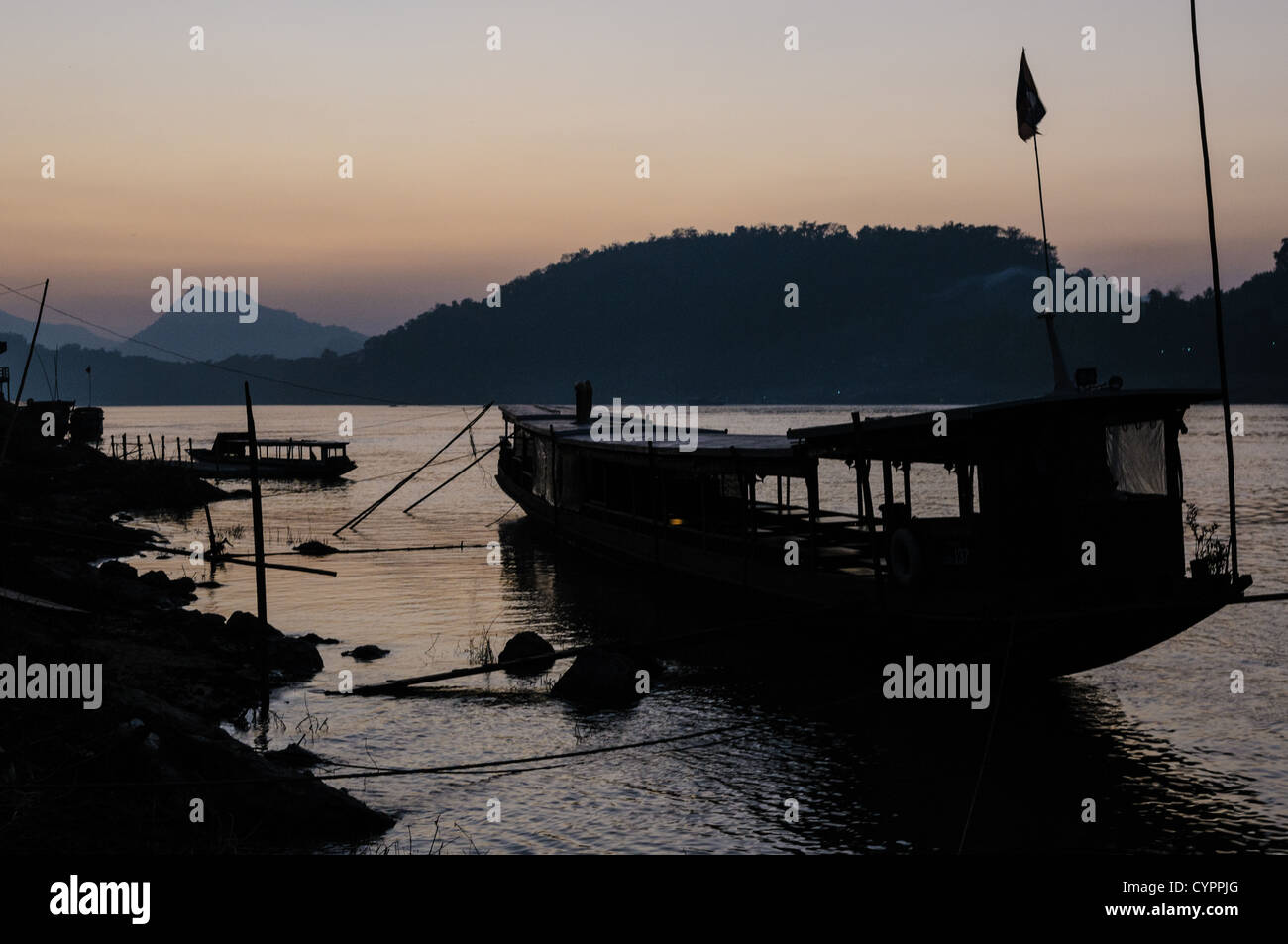 LUANG PRABANG, Laos — coucher de soleil sur le Mékong. Le fleuve Mékong coule près de la ville historique de Luang Prabang dans le nord du Laos. Le fleuve, l'une des principales voies navigables de l'Asie du Sud-est, joue un rôle crucial dans l'écologie, l'économie et la culture de la région. Luang Prabang, site classé au patrimoine mondial de l'UNESCO, est situé au confluent du Mékong et du Nam Khan. Banque D'Images