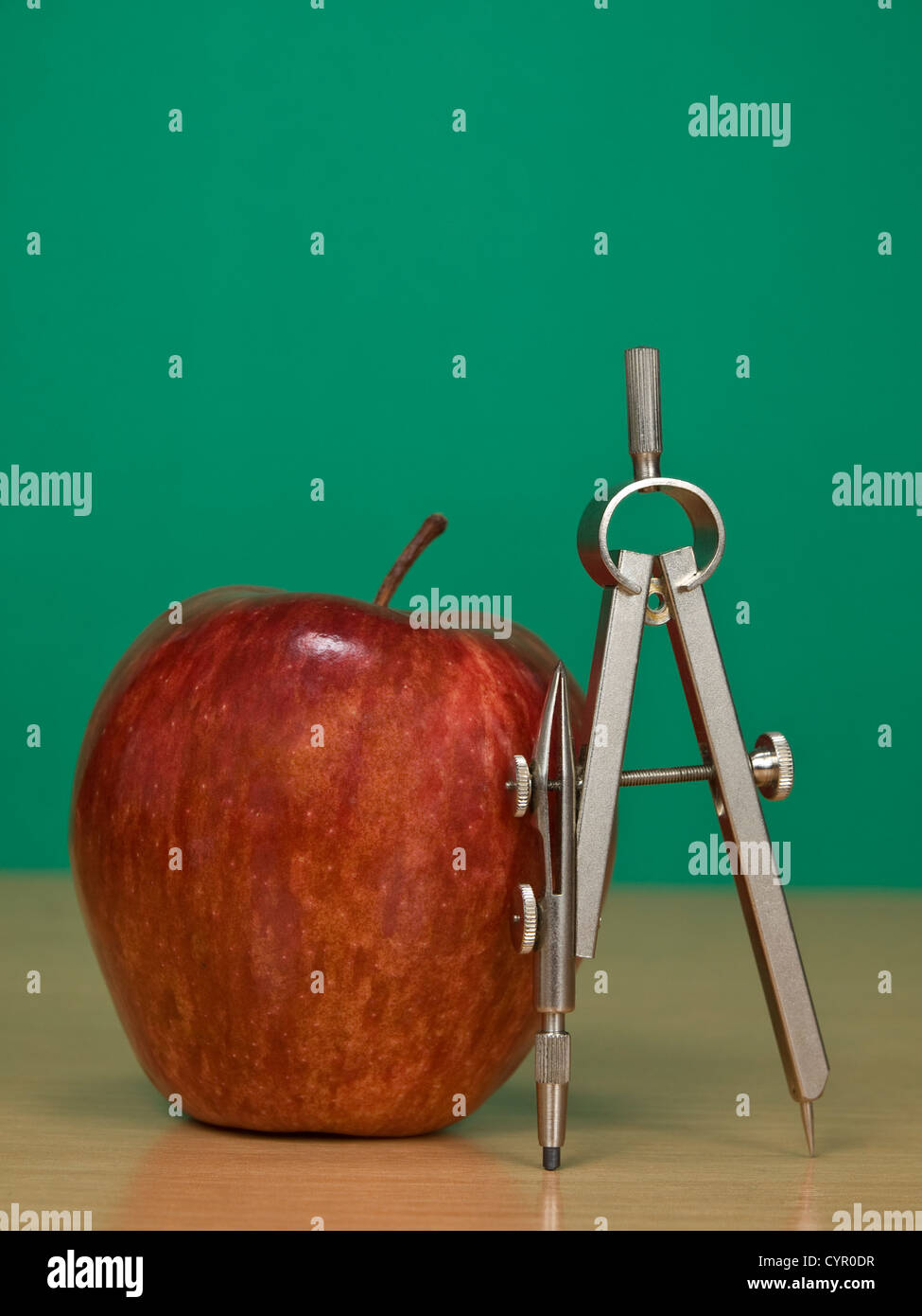 Une pomme rouge et un compas de dessin sur un bureau de classe. Blank chalkboard sur l'arrière-plan. Banque D'Images