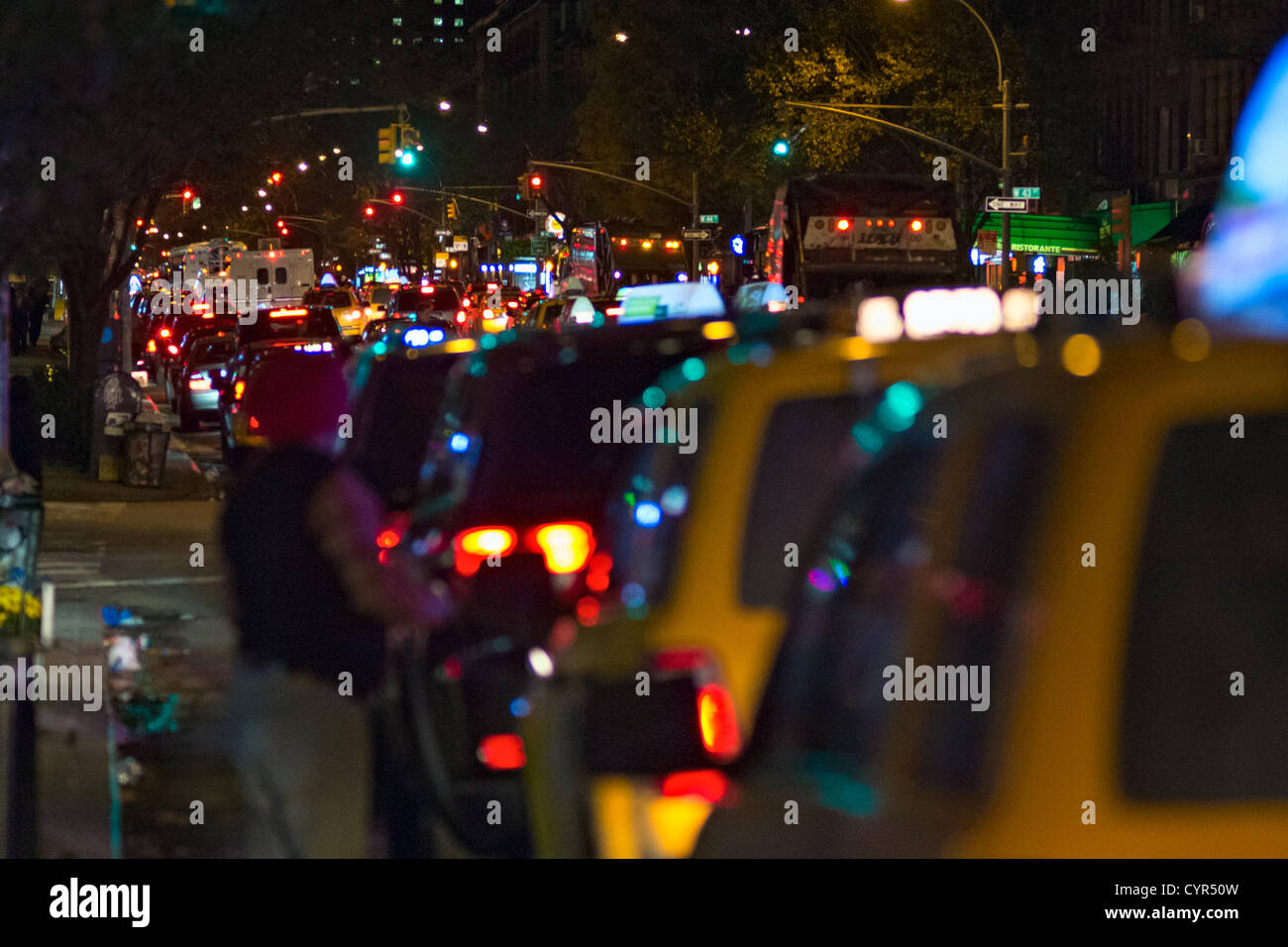 Le 8 novembre 2012, New York, NY, US. Un chauffeur de taxi vérifie la ligne devant lui comme il l'attend à la fin d'une longue ligne à trois volets pour le gaz au New York's Hell's Kitchen quartier, dans les heures précédant le rationnement de l'essence est de commencer dans la ville à cause de la persistance des pénuries de gaz après l'Ouragan Sandy. Banque D'Images