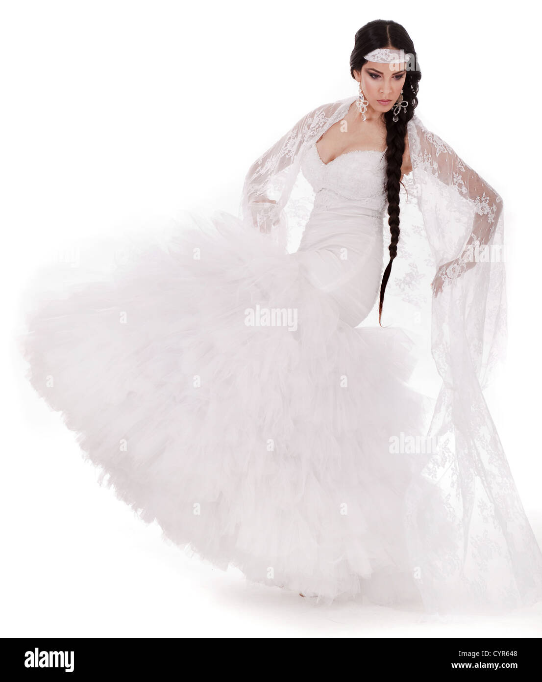 Jeune brunette mariée danse en robe blanche sur fond blanc Banque D'Images