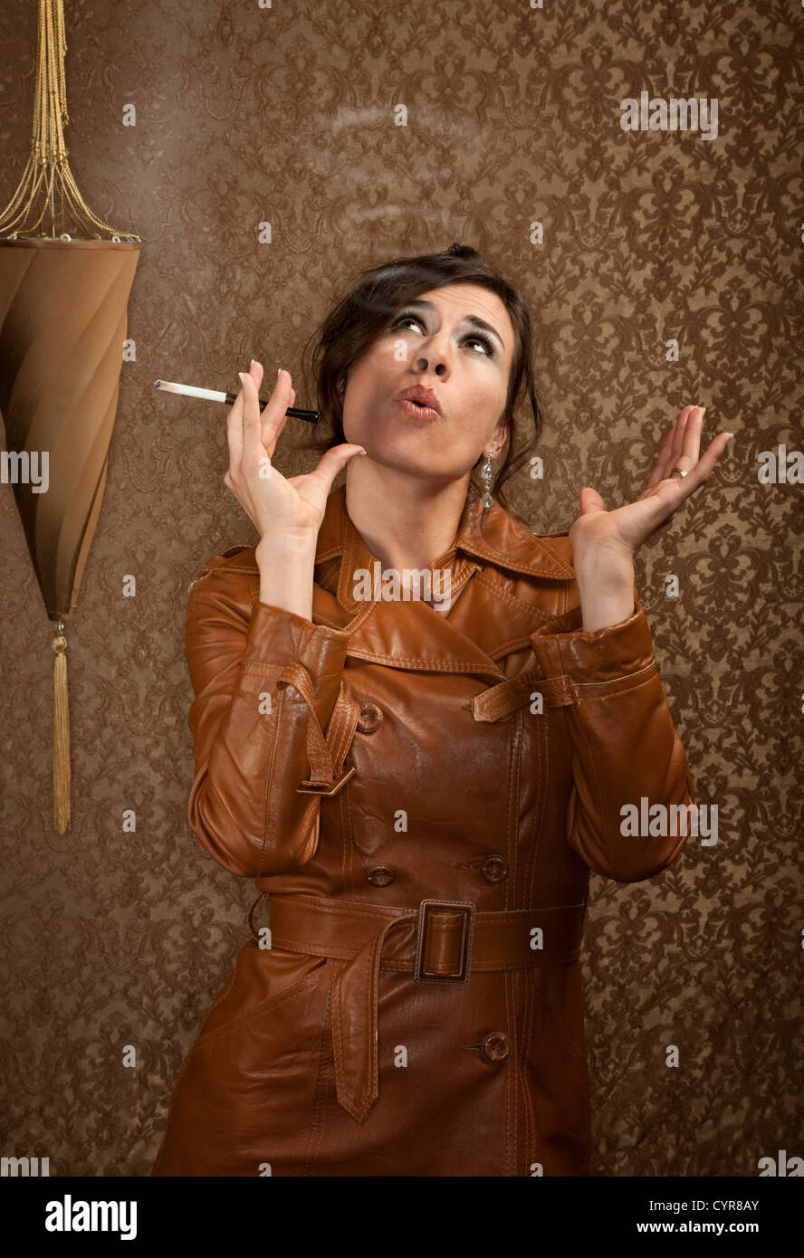 Femme en manteau de cuir sombre avec la cigarette Banque D'Images