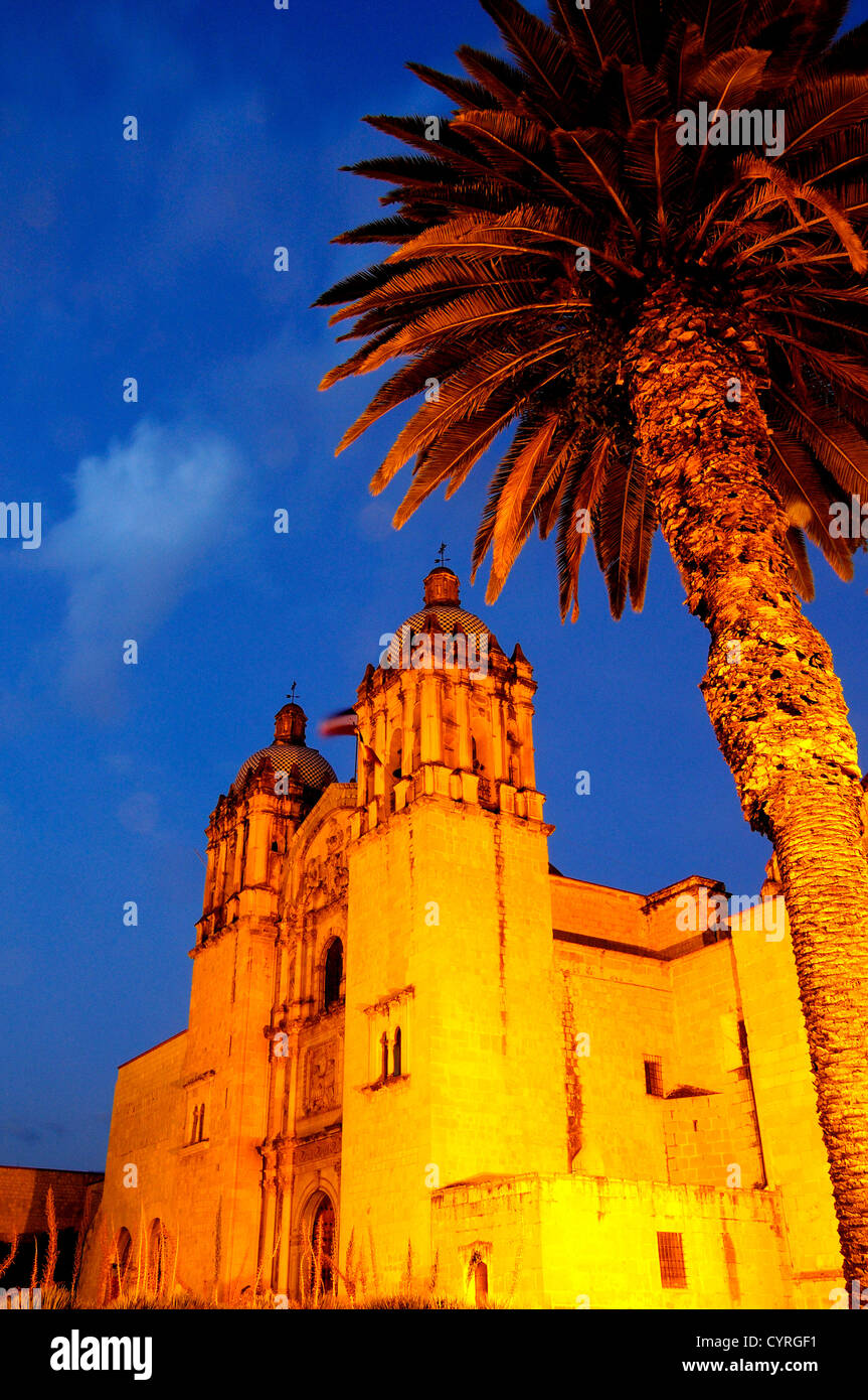 Mexique, Oaxaca, l'église de Santo Domingo, extérieur Baroque éclairé la nuit avec palm arbre en premier plan. Banque D'Images
