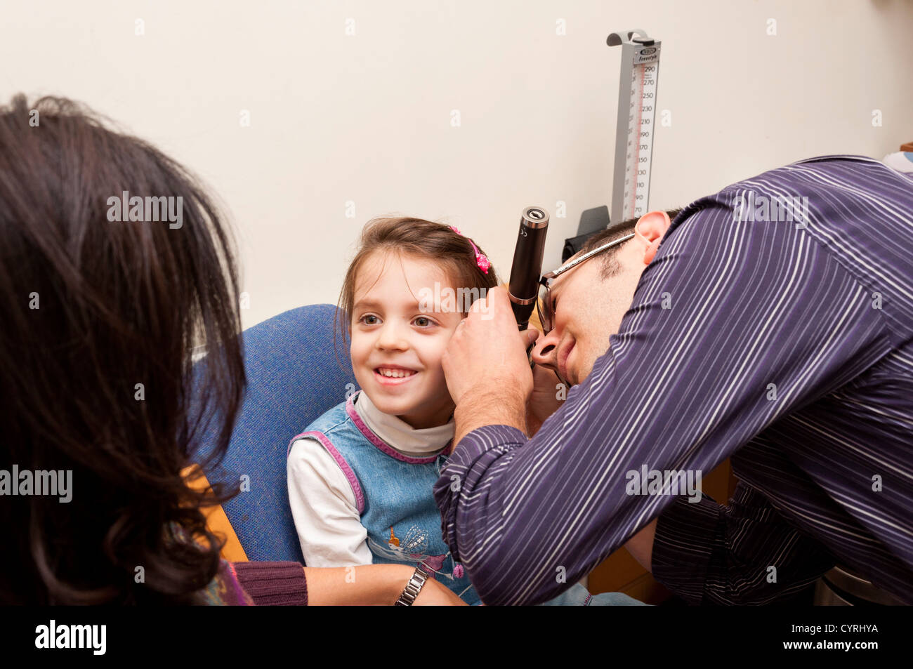 Médecin généraliste du patient chirurgie consultation. GP à l'aide d'un otoscope pour examiner l'oreille d'un enfant. UK Banque D'Images