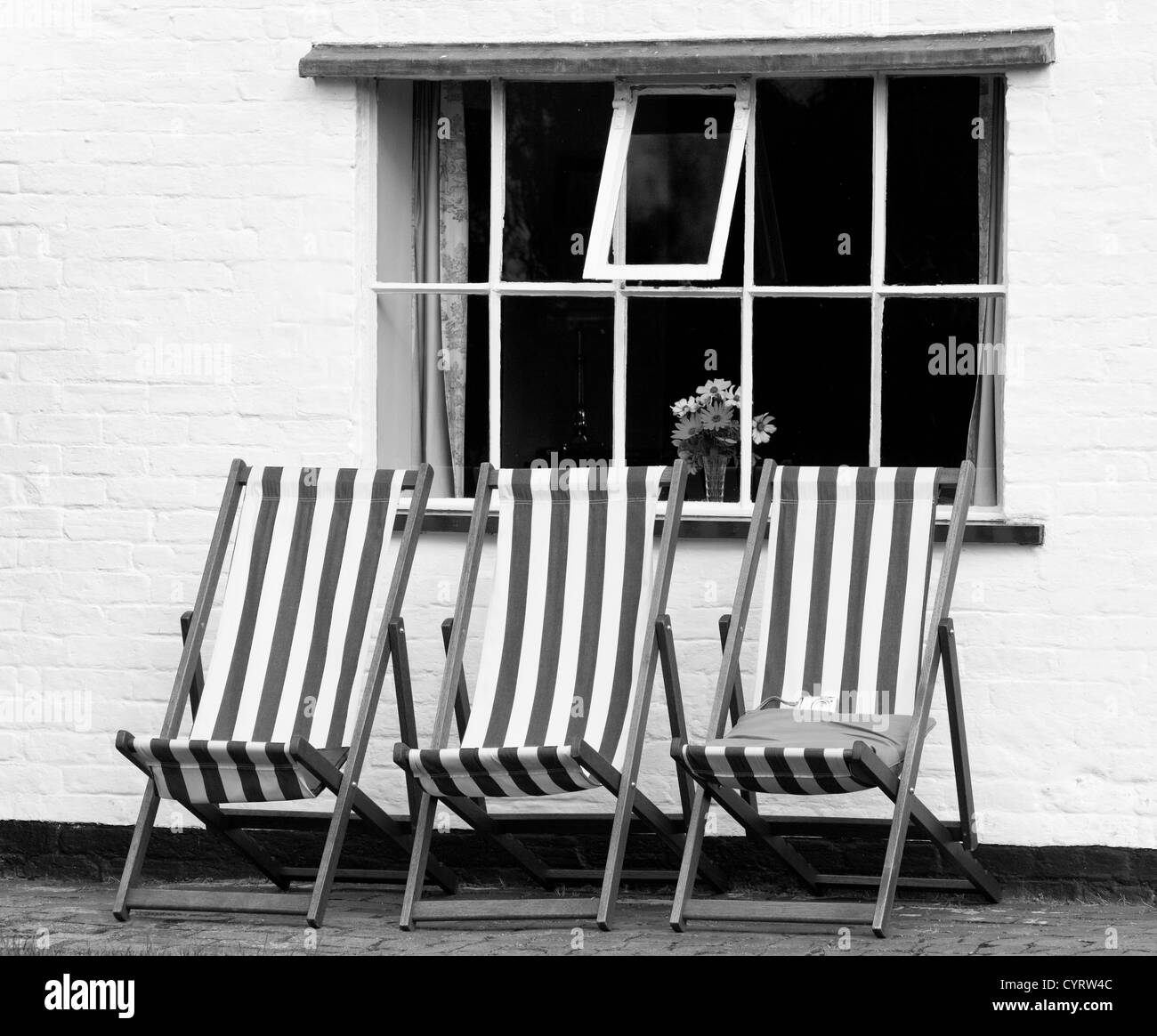 Chaises longues à l'extérieur de la fenêtre d'un chalet en noir et blanc, England, UK Banque D'Images