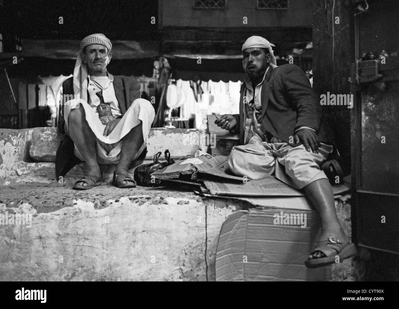 Deux hommes de mâcher le qat tout en vous relaxant, noir et blanc, Sanaa, Yémen Banque D'Images
