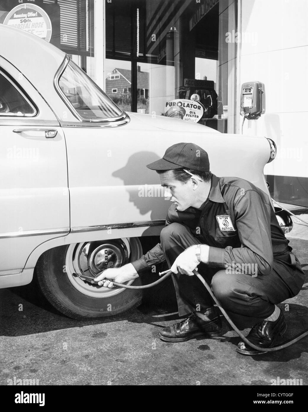 Homme de service en remplaçant l'air des pneus de voiture Banque D'Images