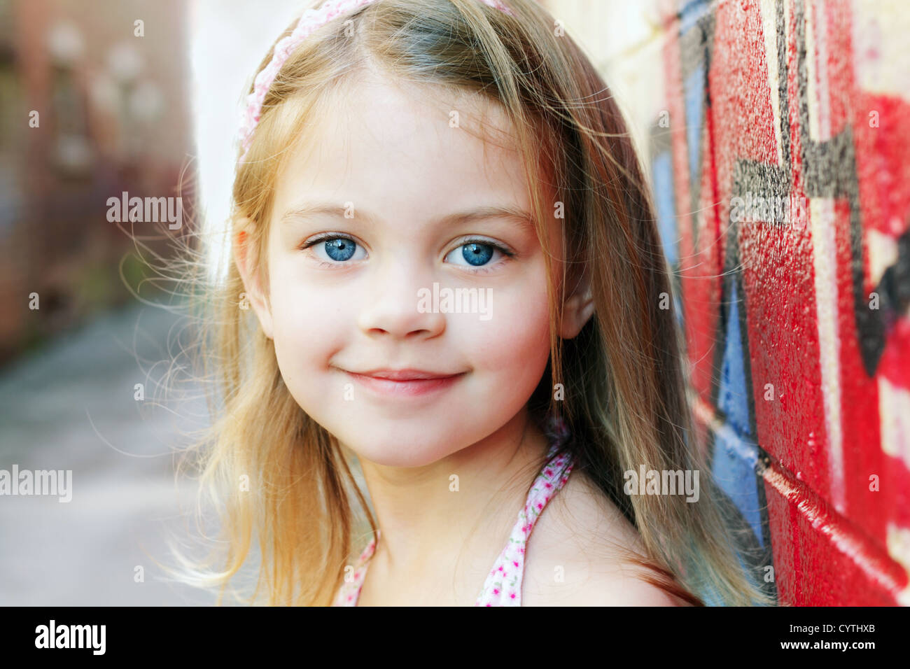 Petite fille dans un cadre urbain, sourit à la caméra. Banque D'Images