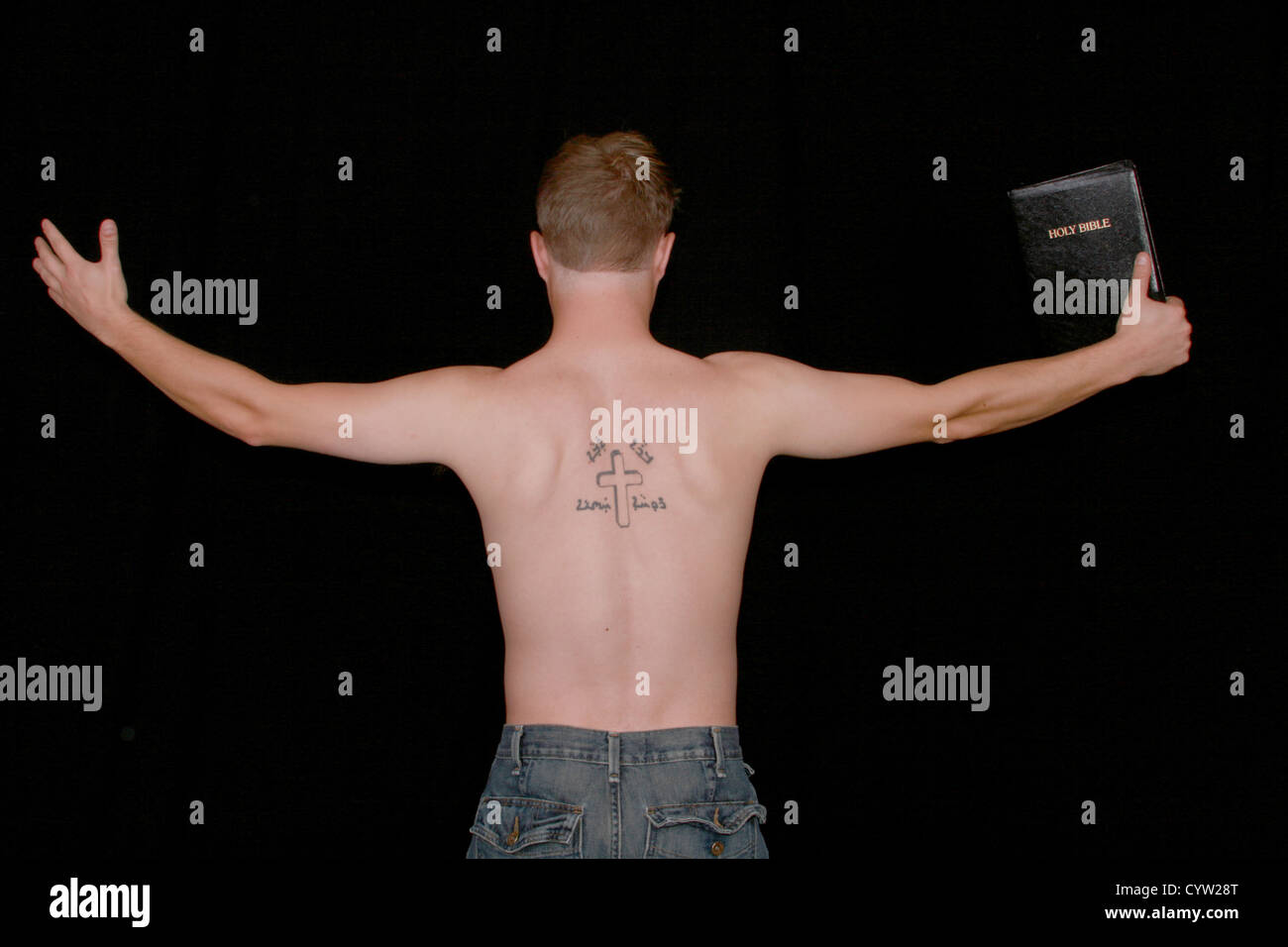 Un homme prêchant avec un crucifix et aramiac écrit tatoué sur son dos. Banque D'Images