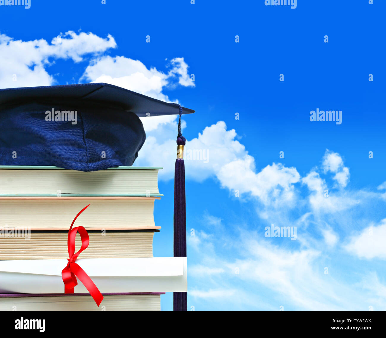 Pile de livres avec cap et diplôme contre le ciel bleu Banque D'Images