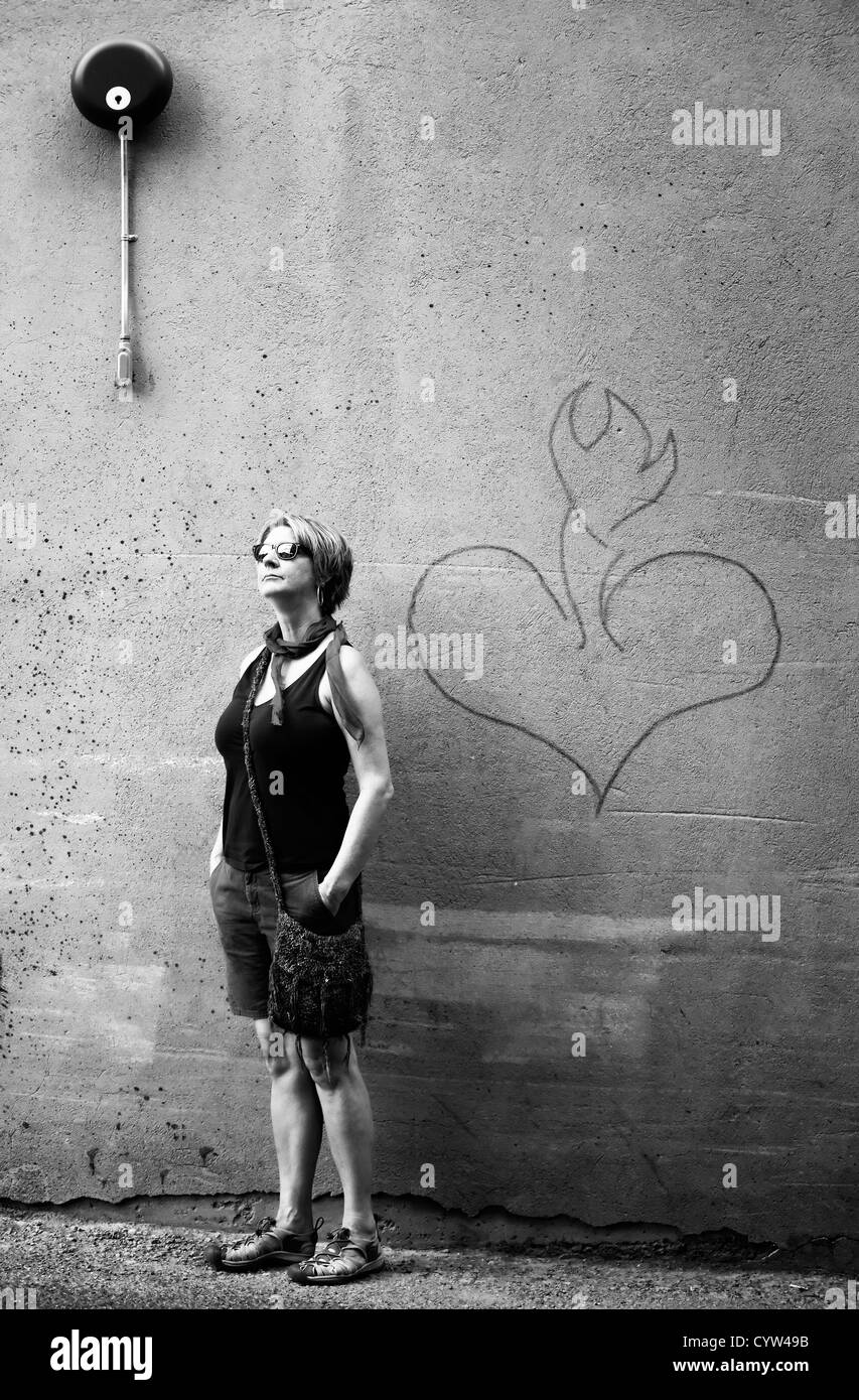 Woman in front of mur de ciment avec un coeur Banque D'Images