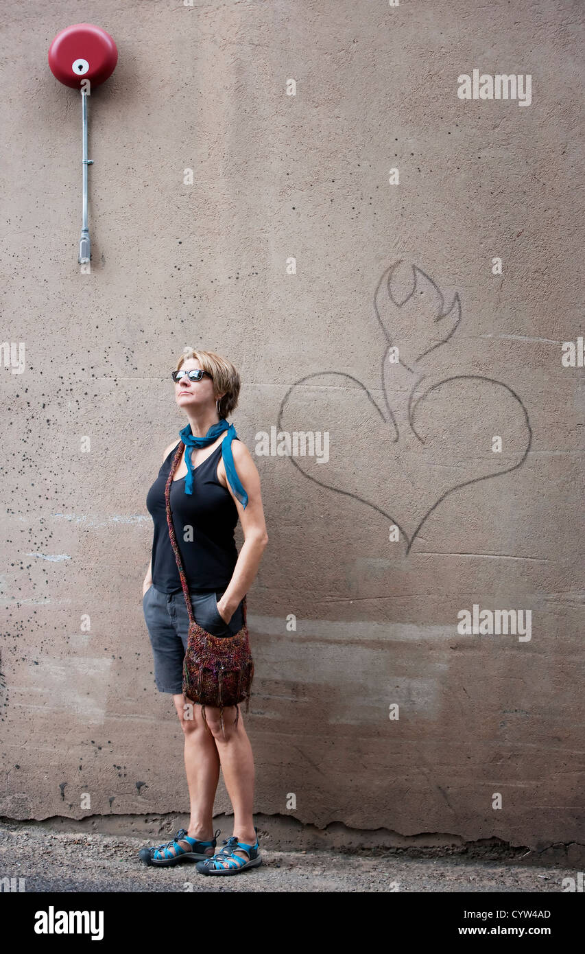Woman in front of mur de ciment avec un coeur Banque D'Images