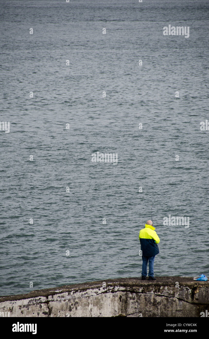 BEAUMARIS, pays de Galles - Un homme pêche à Beaumaris sur l'île d'Anglesey, sur la côte nord du pays de Galles, Royaume-Uni. CopySpace avec l'eau. La pittoresque ville côtière de Beaumaris, située sur l'île d'Anglesey au pays de Galles, offre aux visiteurs un aperçu de la riche histoire de la région, avec son château médiéval, son architecture victorienne et son bord de mer pittoresque. Beaumaris a été classé au patrimoine mondial de l'UNESCO et continue à charmer les voyageurs avec ses monuments bien conservés et sa beauté naturelle étonnante. Banque D'Images