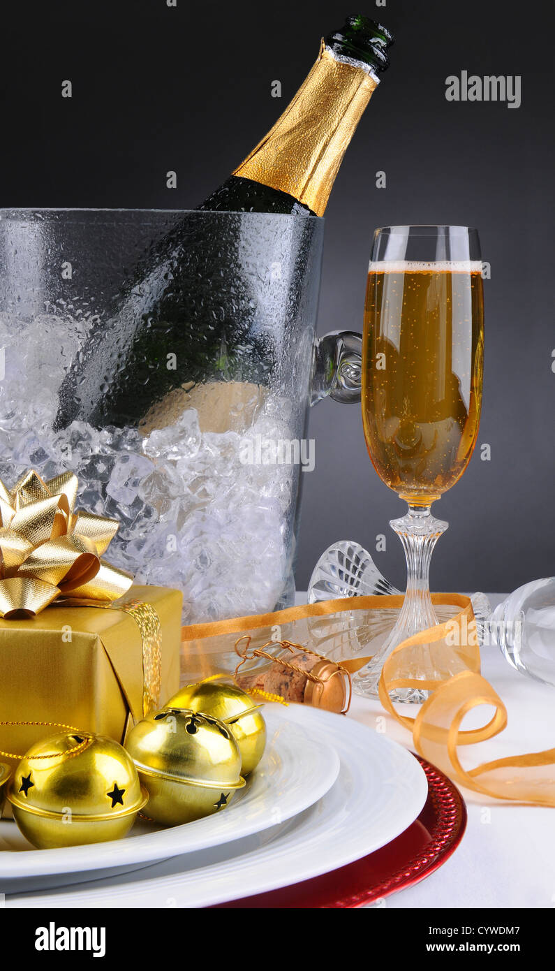Verre à Champagne seau à glace et sur une table de vacances décorée avec des présents, du ruban et des cloches. Banque D'Images