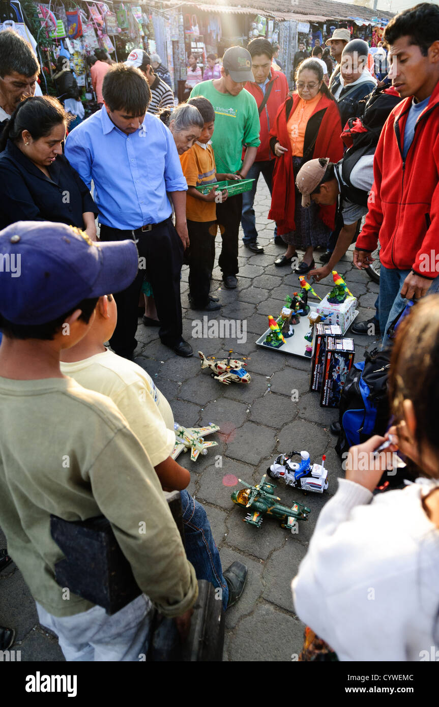 Les enfants et les adultes regarder des démonstrations de jouets au marché principal à Antigua, Guatemala. Banque D'Images