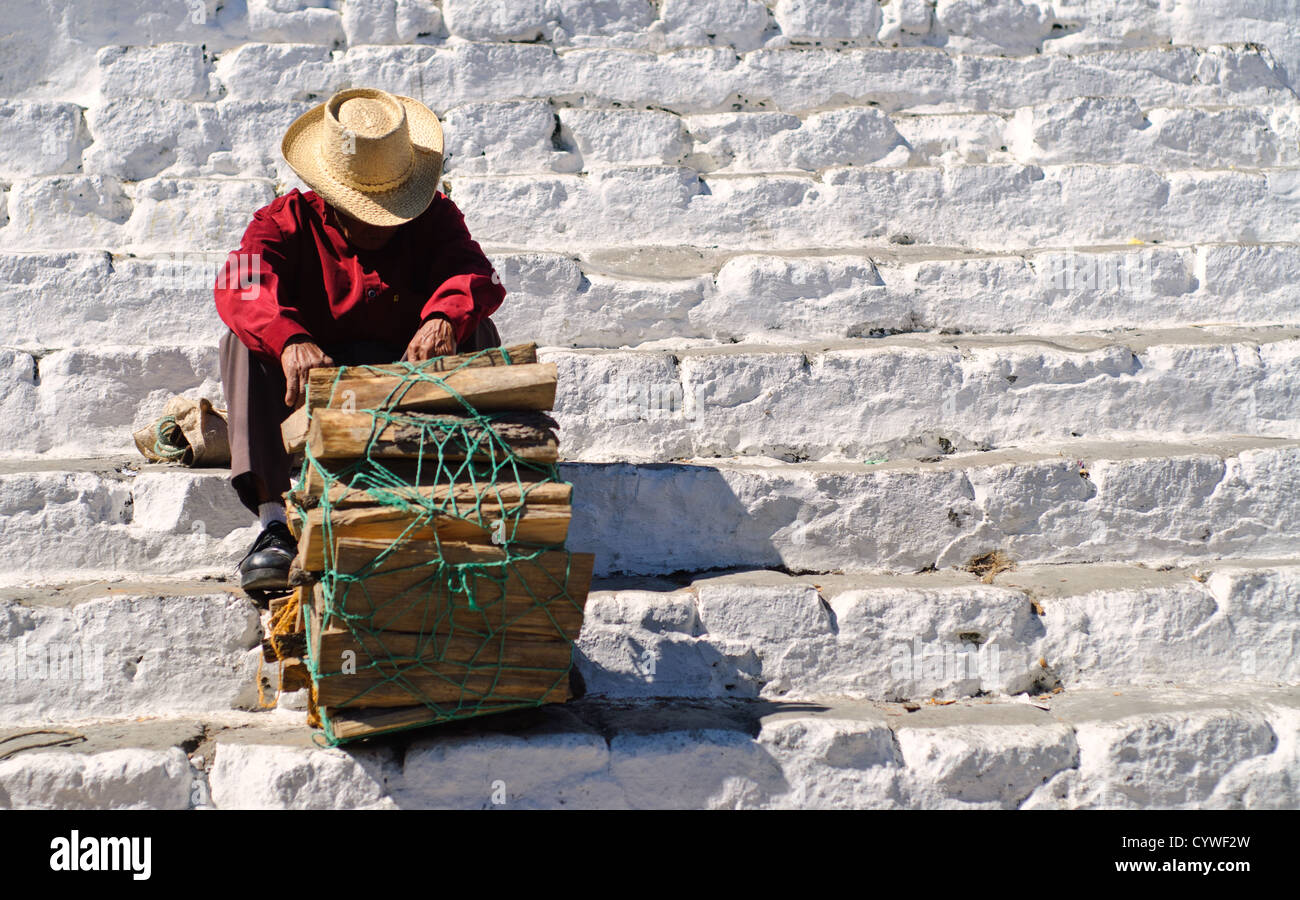 CHICHICASTENANGO, Guatemala - un homme vendant du bois se trouve en appui sur les étapes de Capilla del Calvario, une église blanchie à la chaux au milieu de Chichicastengo en face de l'église Santo Tomas. Chichicastenango est une ville maya dans les hautes terres guatémaltèques environ 90 milles au nord-ouest de la ville de Guatemala et à une altitude de près de 6 500 pieds. Il est plus célèbre pour son marché le dimanche et le jeudi. Banque D'Images