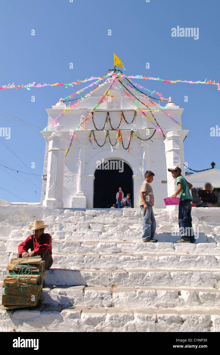 CHICHICASTENANGO, Guatemala - un homme vendant du bois se trouve en appui sur les étapes de Capilla del Calvario, une église blanchie à la chaux au milieu de Chichicastengo en face de l'église Santo Tomas. Chichicastenango est une ville maya dans les hautes terres guatémaltèques environ 90 milles au nord-ouest de la ville de Guatemala et à une altitude de près de 6 500 pieds. Il est plus célèbre pour son marché le dimanche et le jeudi. Banque D'Images