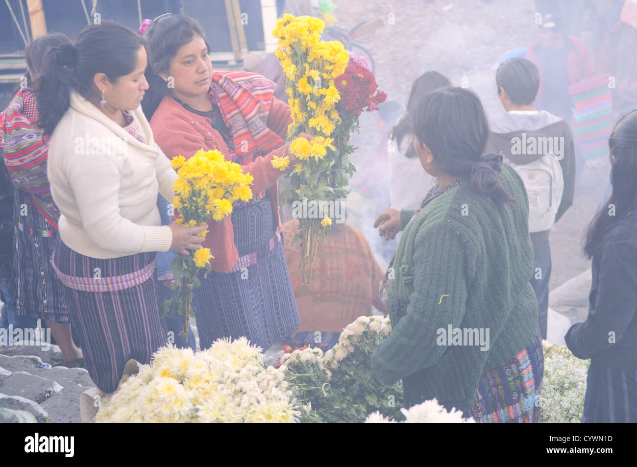 CHICHICASTENANGO, Guatemala - Femmes vente de fleurs dans la Chichicastengo marché. Ils sont sur les marches de l'église Santo Tomas et la fumée est de prière Maya local leaders (connu comme chuchkajaues) de l'encens copal et résine. Chichicastenango est une ville maya dans les hautes terres guatémaltèques environ 90 milles au nord-ouest de la ville de Guatemala et à une altitude de près de 6 500 pieds. Il est plus célèbre pour son marché le dimanche et le jeudi. Banque D'Images