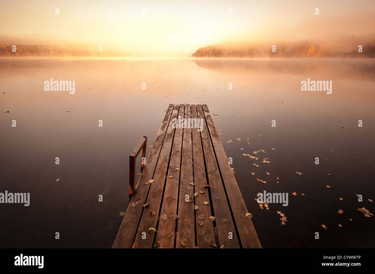 Petite jetée en bois sur le lac encore matin brumeux d'automne, avec soleil levant Banque D'Images