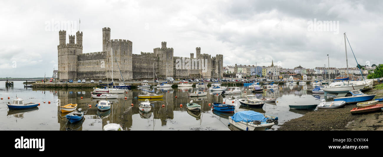 CAERNARFON, Pays de Galles - un panorama du château à l'arrière-plan avec des bateaux amarrés sur la River à Seiont au premier plan dans le nord-ouest du château de Caernarfon au Pays de Galles. Un château s'élevait à l'origine sur le site remontant à la fin du xie siècle, mais à la fin du 13e siècle, le Roi Edward J'ai commandé une nouvelle structure qui se tient à ce jour. Il possède des tours et est l'un des mieux conservés de la série de châteaux-QUE J'ai commandé. Banque D'Images