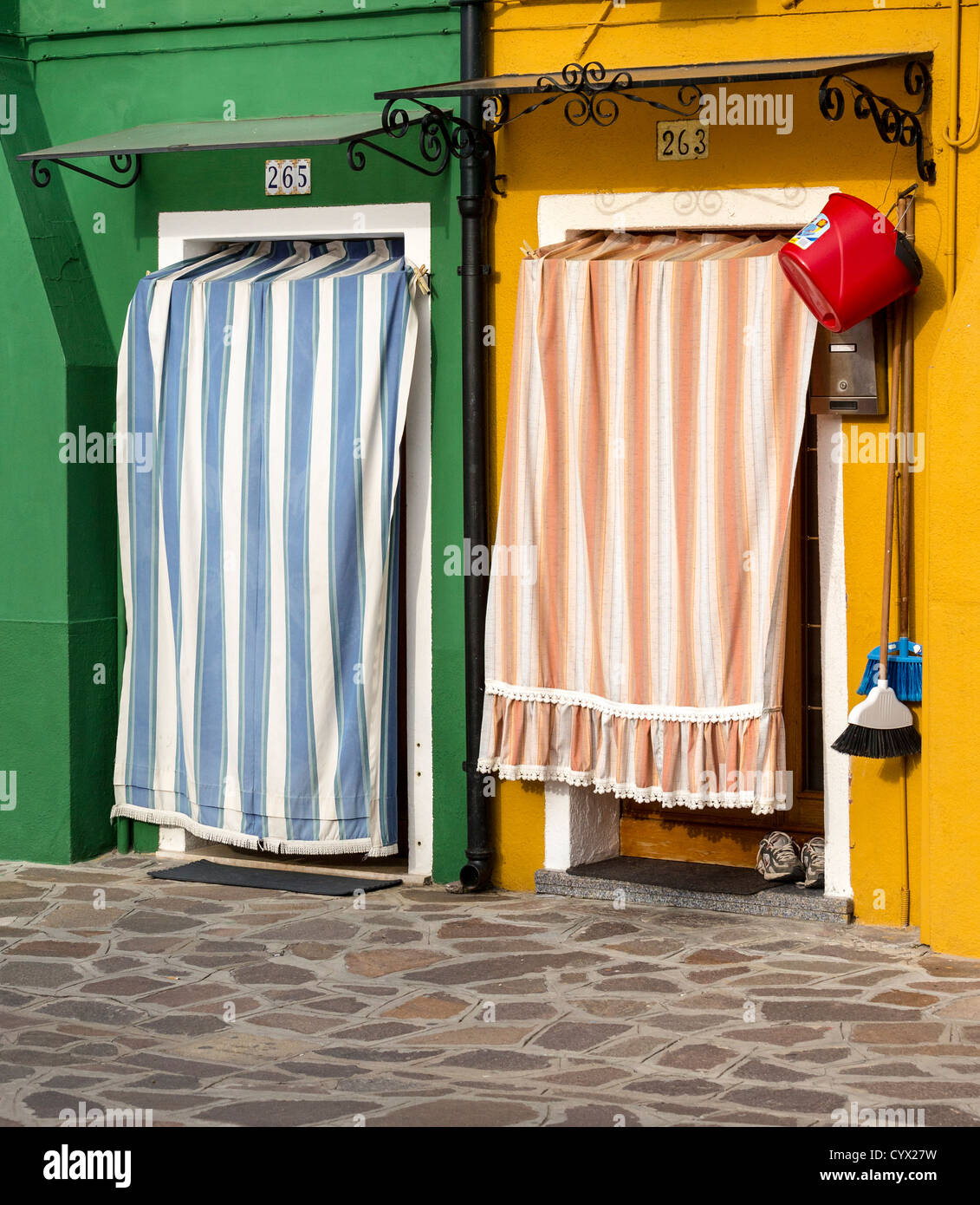 Deux maisons peintes de couleurs vives en Burano avec rideaux à rayures / auvents couvrant leurs portes avant Banque D'Images