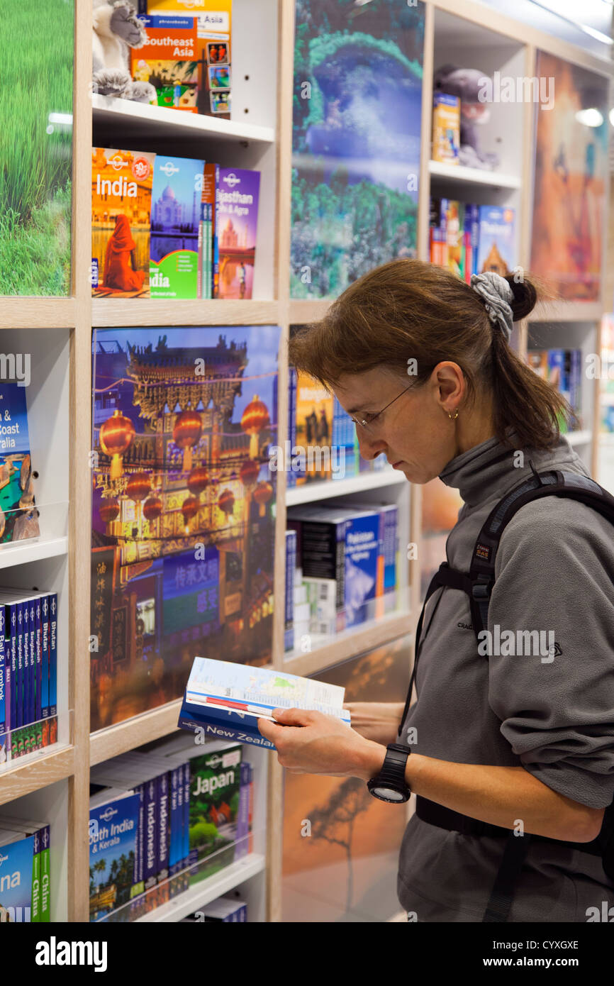 Backpacker à Lonely Planet guide books dans le Lonely Planet shop à l'aéroport de Manchester, Manchester, Royaume-Uni. Banque D'Images